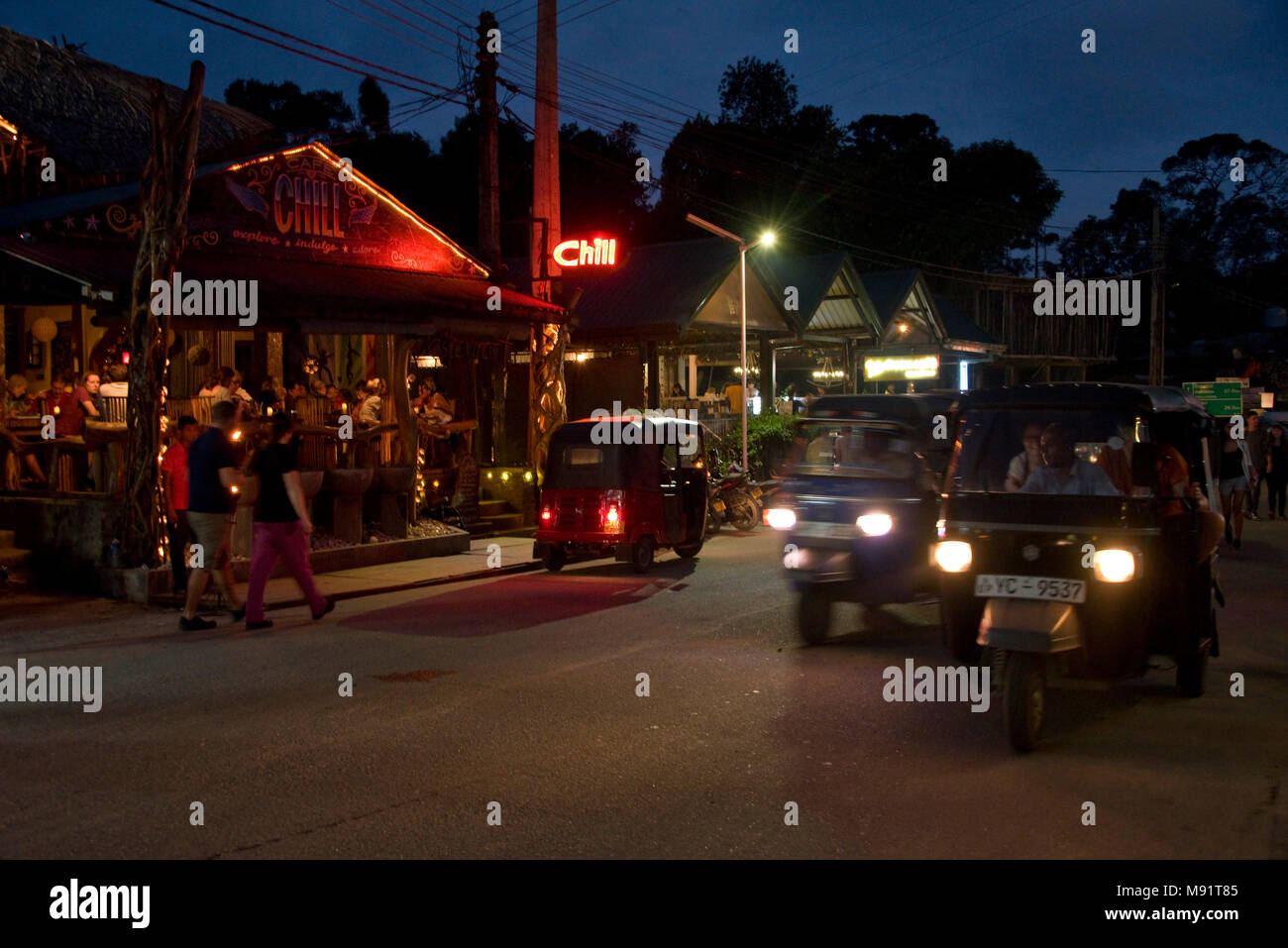 La calle principal en ella tarde noche con Tuk Tuks, restaurantes, bares, los turistas y lugareños. Velocidad de obturación lenta e ISO alto para el desenfoque de movimiento. Foto de stock