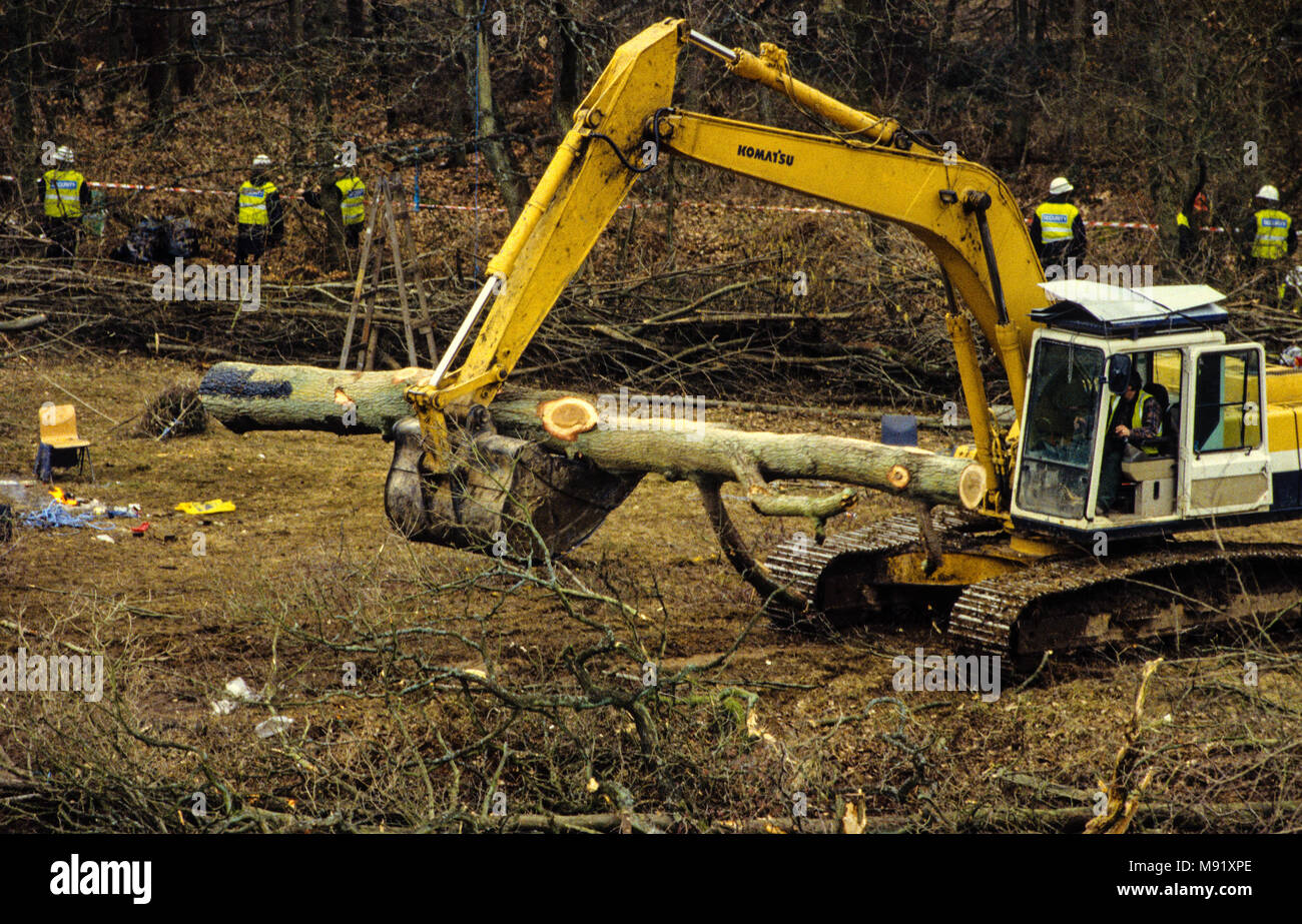 Digger moviendo los árboles talados custodiadas por guardias de seguridad, Carretera de circunvalación de Newbury, la construcción y las protestas , en Newbury, Berkshire, Inglaterra. Reino Unido, GB. Foto de stock
