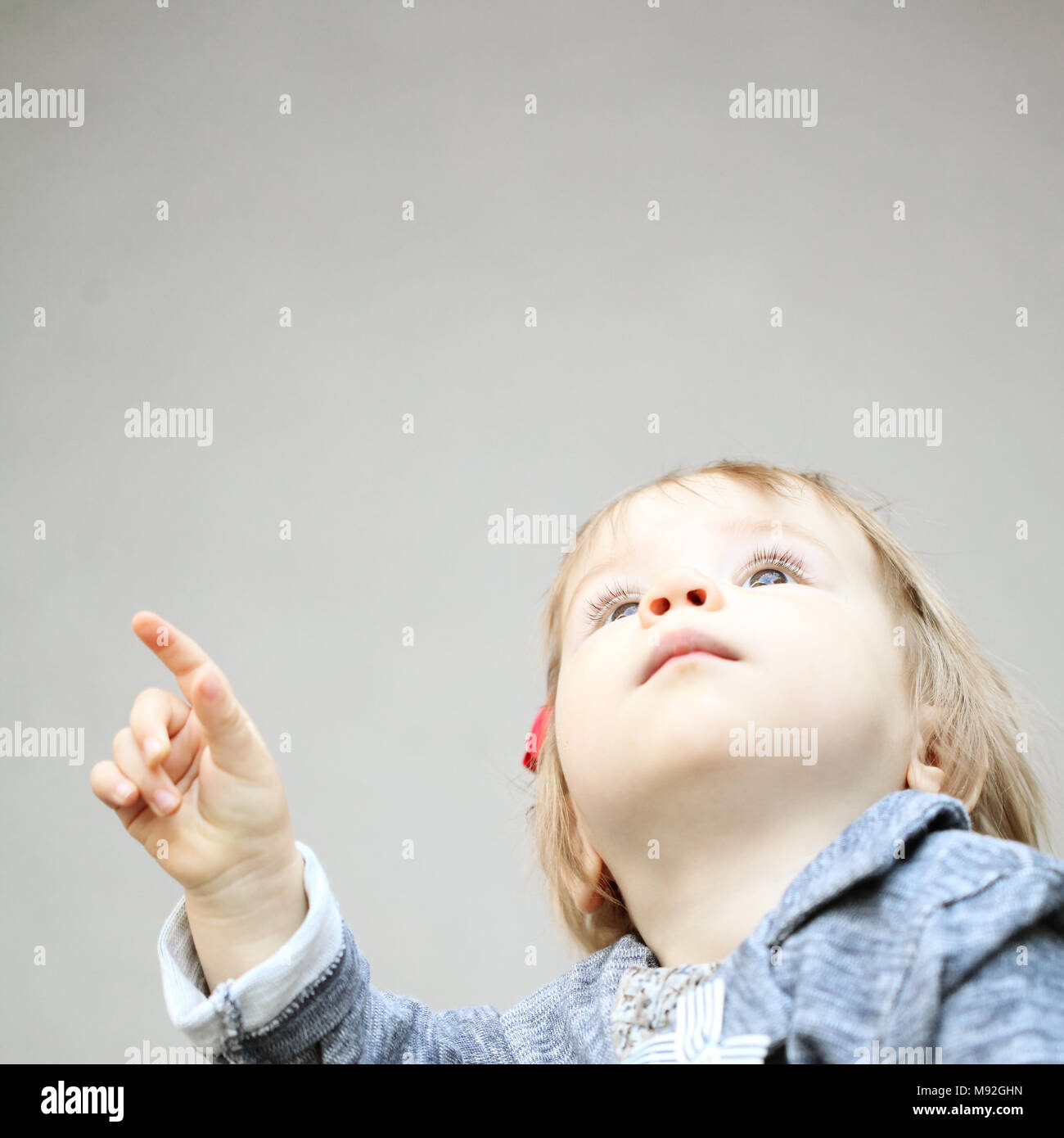 Lindo niño apuntando y mirando hacia arriba Foto de stock