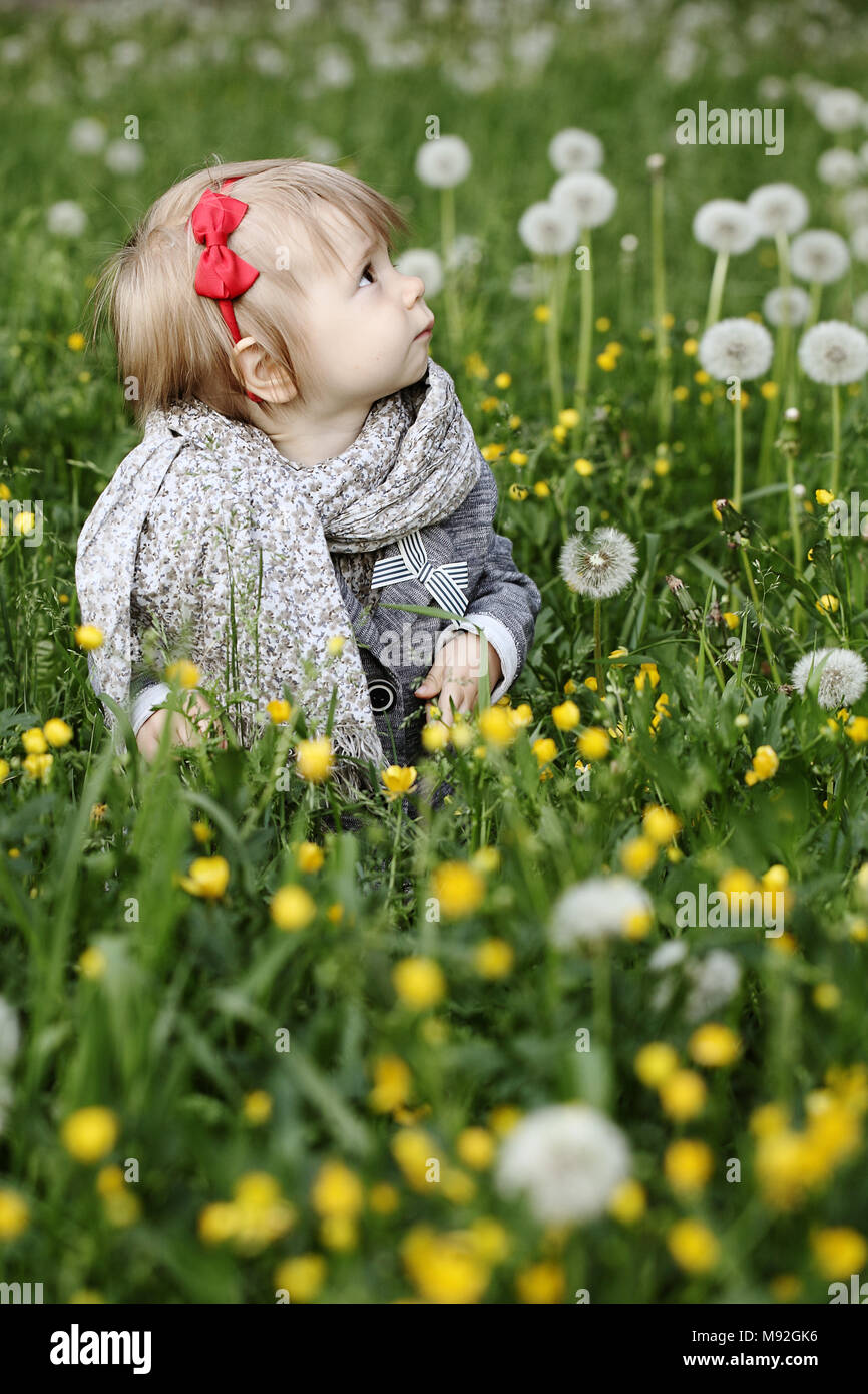 Cute Little Girl en la hierba mirando hacia arriba Foto de stock