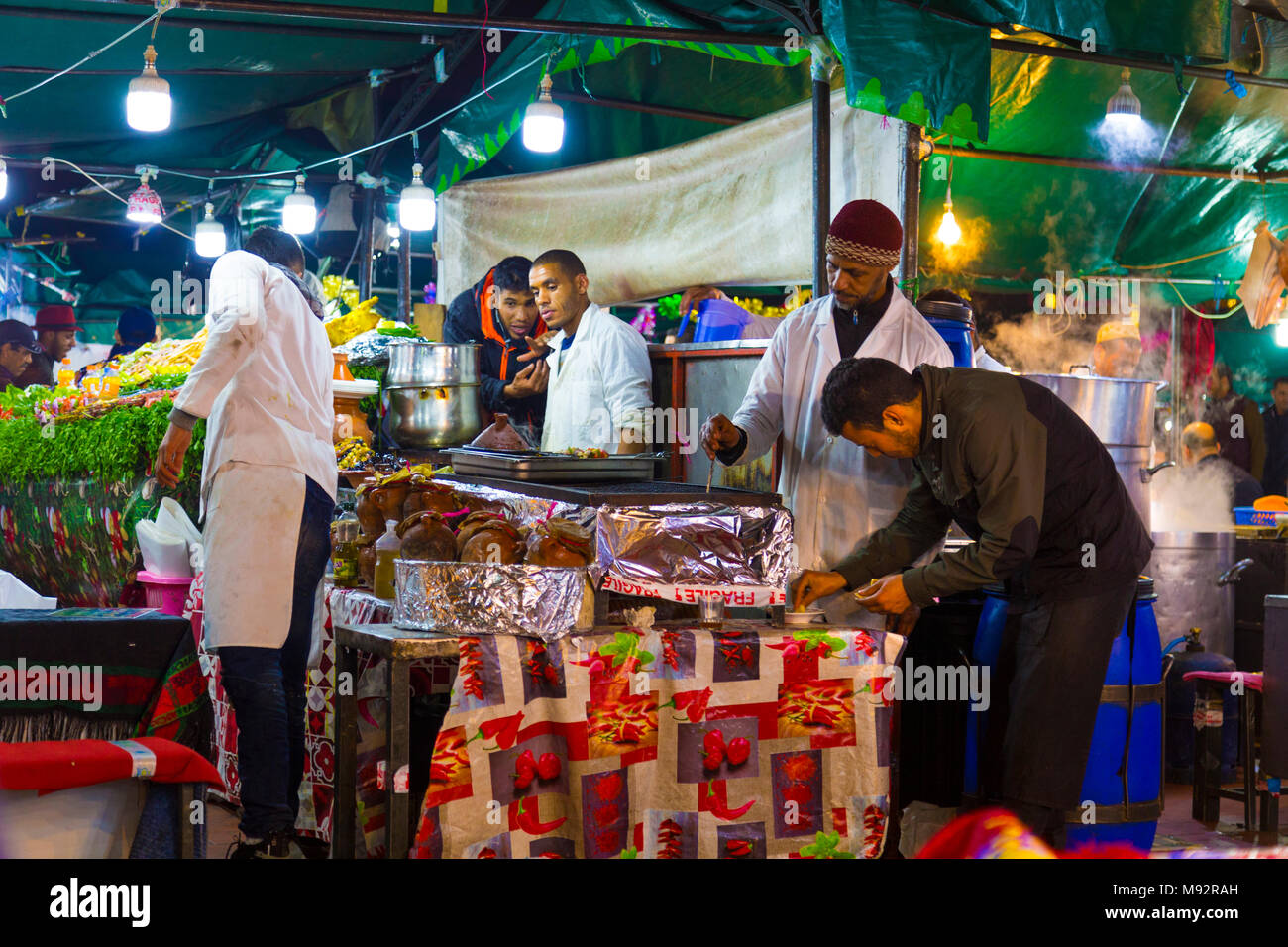 Los chefs cocinando en un puesto de comida en la plaza Djemaa el-Fna, el mercado de la Medina de Marrakech, Marruecos Foto de stock