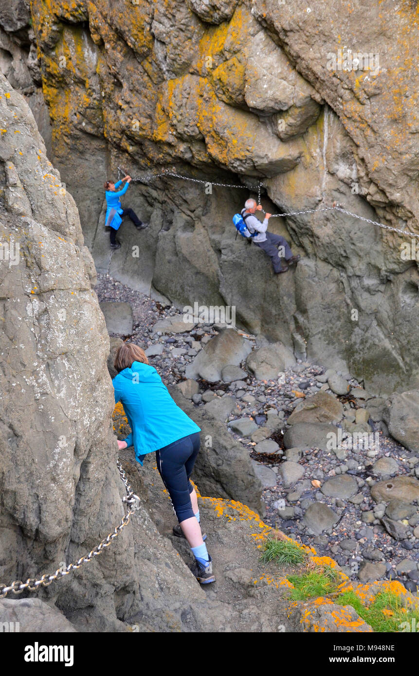 Un grupo de personas hacer el paseo en la cadena costera rocosa Elie, Fife Foto de stock