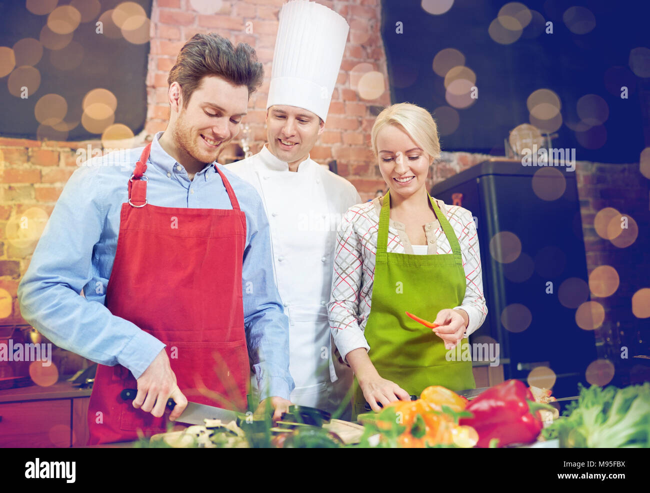 Feliz pareja masculina y chef cocinando en la cocina Foto de stock