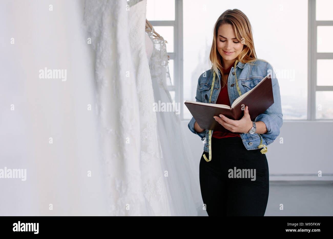 Sastre femenino escrito en un diario mientras está de pie vestido de novia  tienda. La indumentaria femenina diseñador que trabaja en la tienda de ropa  nupcial Fotografía de stock - Alamy