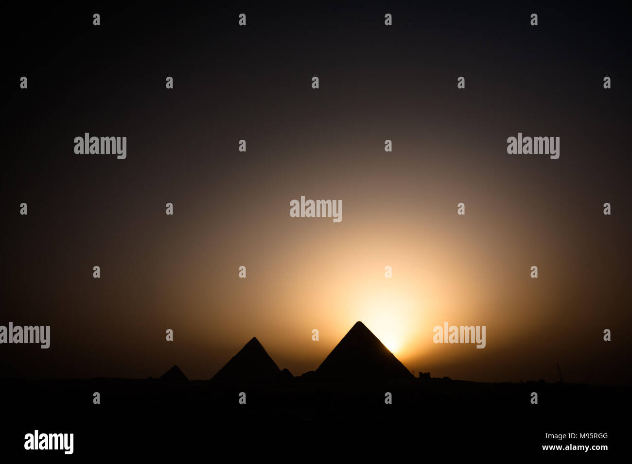 El sol ha caído por detrás de la Gran Pirámide lanzando un majestuoso aura de luz en el cielo junto una de las Siete Maravillas del Mundo, Giza, El Cairo. Foto de stock