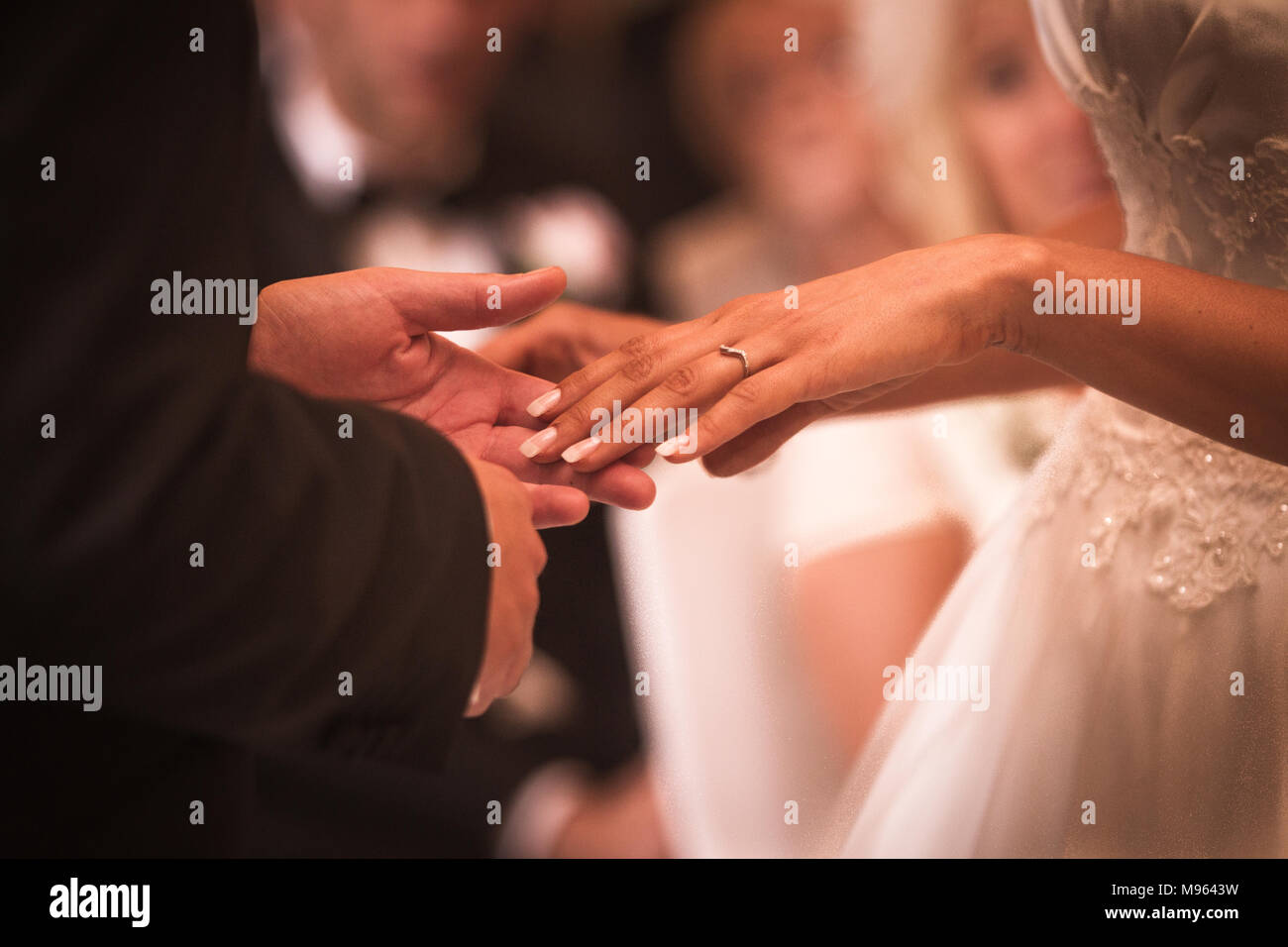 El novio sostiene la mano de la novia después de colocar el anillo de bodas en el dedo Foto de stock