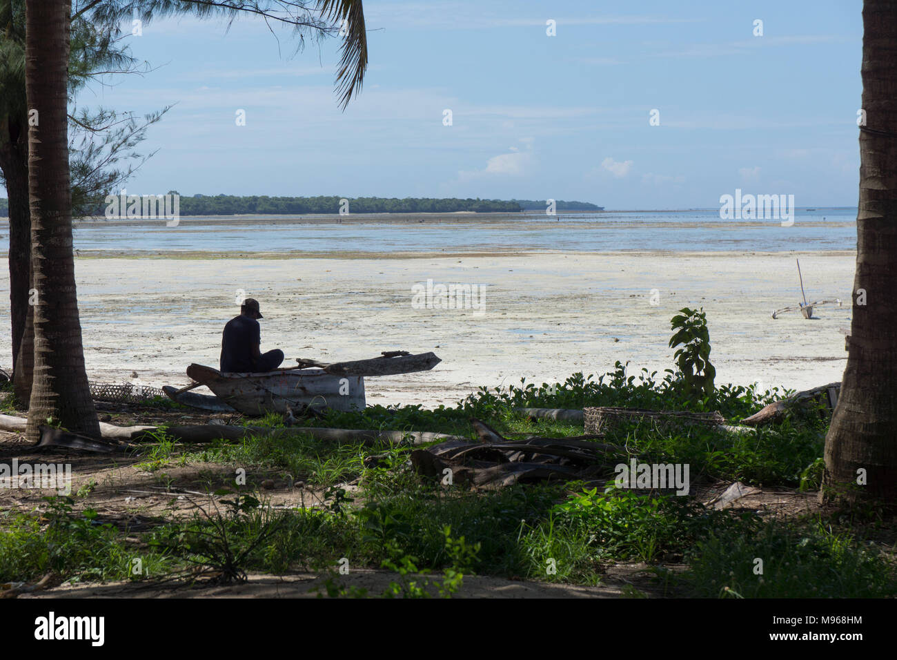 Pescador tendiendo a redes en la sombra de las palmeras en Zanzíbar Foto de stock