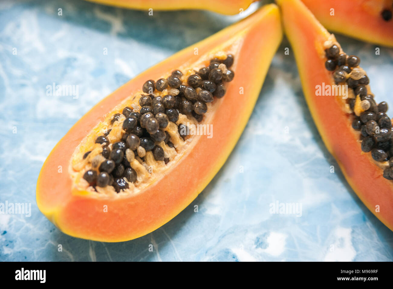 Jugosas rebanadas de papaya madura sobre un fondo azul. Frutas exóticas, comida saludable. Foto de stock