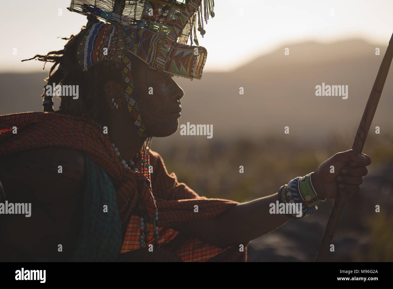 Hombre masai en vestimentas tradicionales sentado en campo Foto de stock