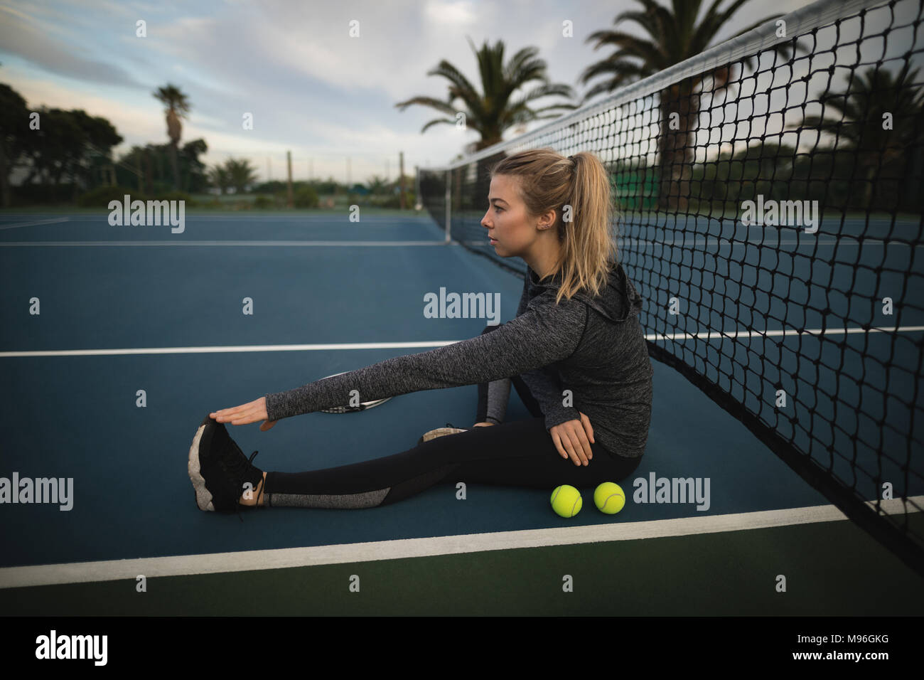 Mujer, jugador de tenis y piernas estiradas en la cancha de tenis