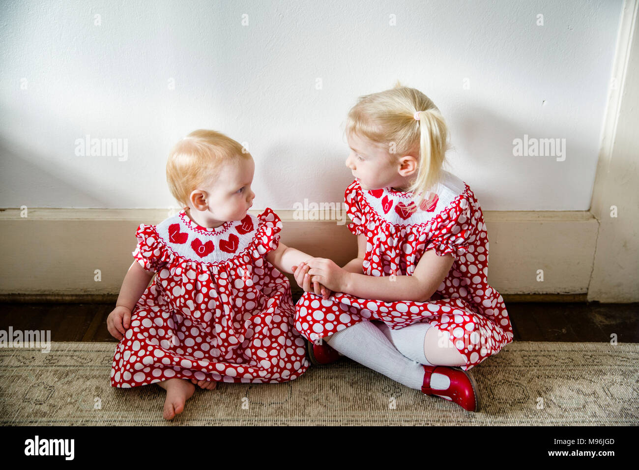 Bebé y mirando uno al otro en mismo vestido rojo Fotografía de stock - Alamy