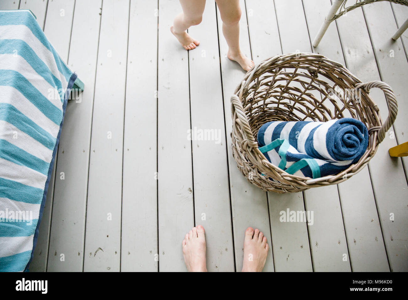 Cesta de mimbre con toallas, junto a los pies de los niños Foto de stock