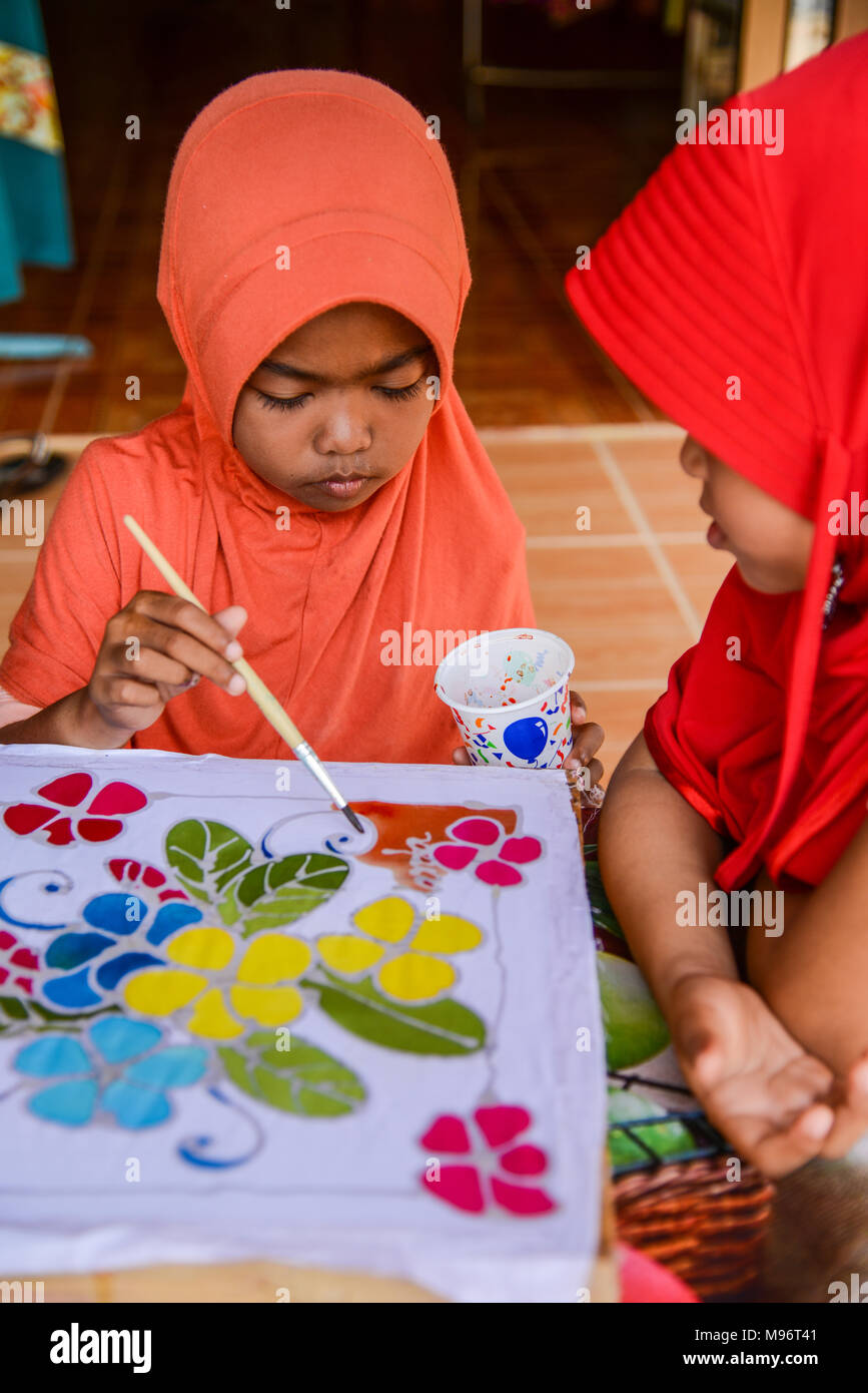 En Krabi, Tailandia - Mayo 2, 2015: Naranja Vestido niña pintura sobre  telas batik mientras vestido rojo chica mirando en la isla de Lanta batik  de Krabi, Tailandia Fotografía de stock - Alamy