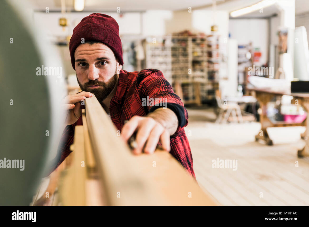 Hombre examinando la madera en el taller Foto de stock