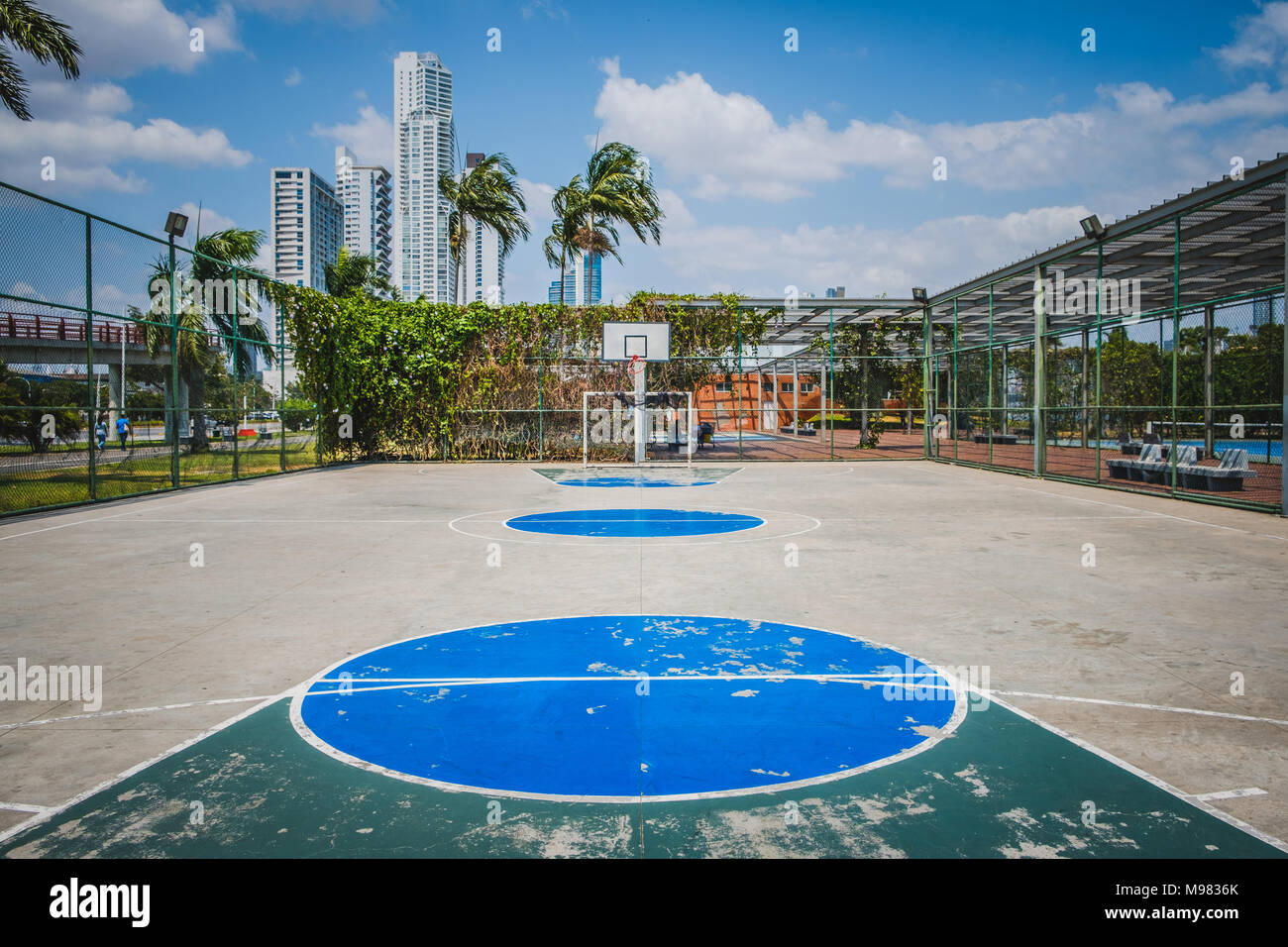 Campo de deportes, cancha de baloncesto con la ciudad de fondo: Foto de stock
