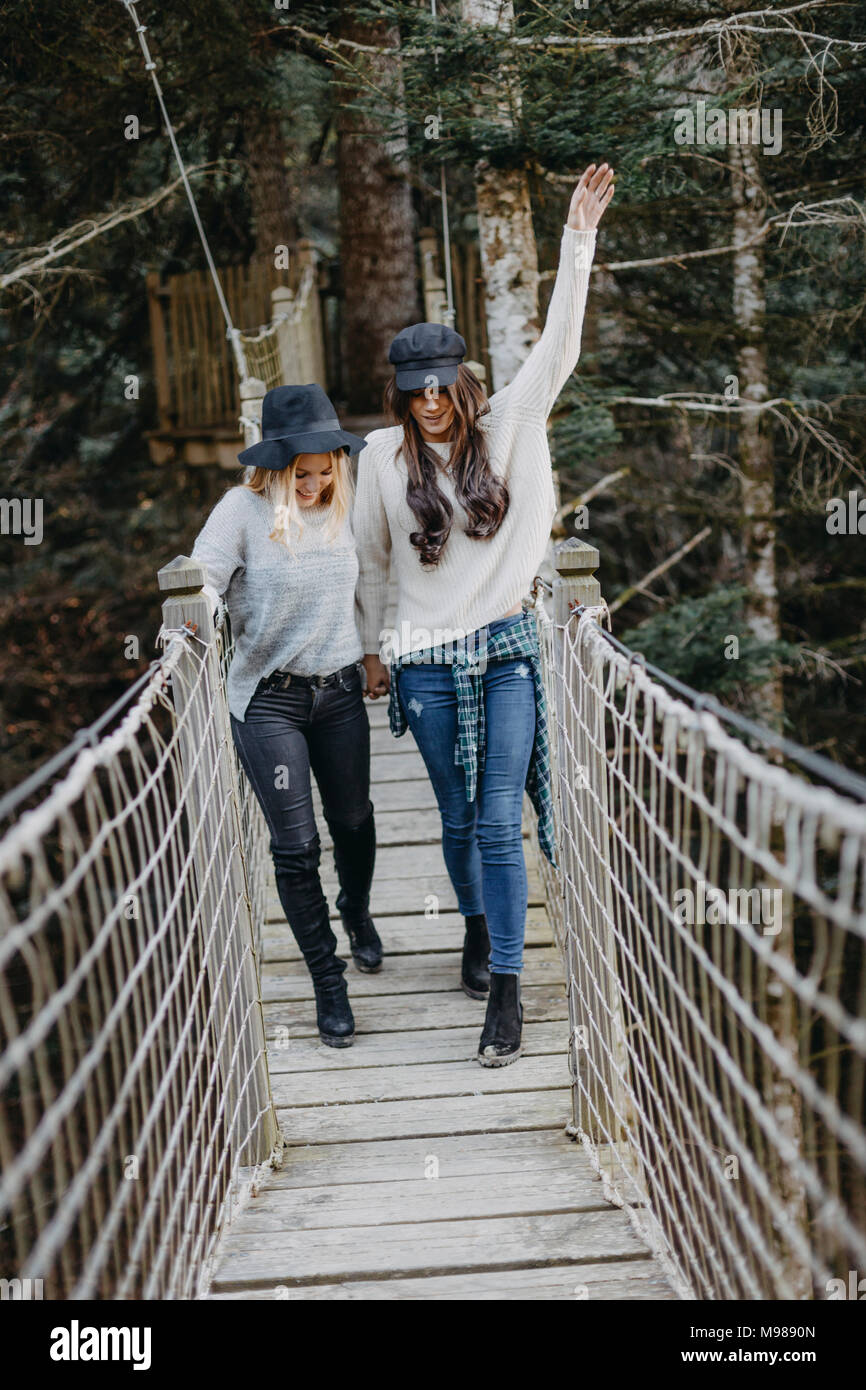 Dos mujeres jóvenes felices caminando sobre una suspensión juntos Foto de stock