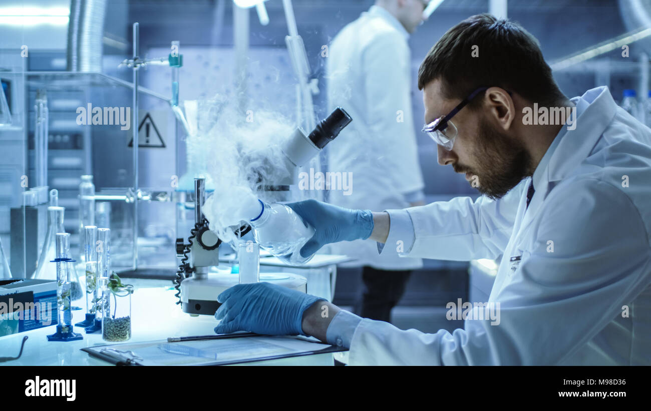 En un laboratorio de Investigación Química científico mezcla de fumar compuestos en vasos de precipitados. Foto de stock