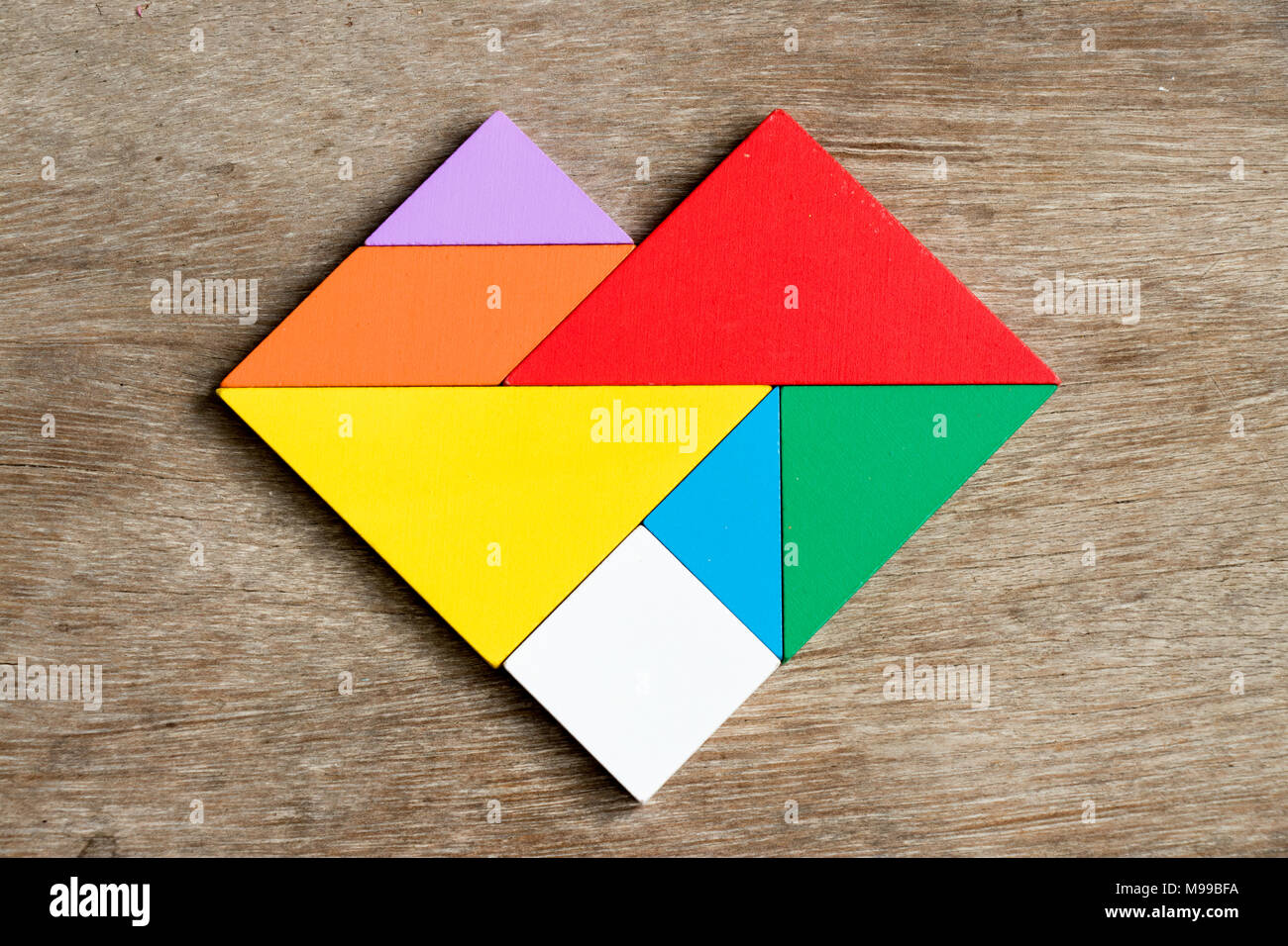 Tangram coloridas en forma de corazón sobre fondo de madera Fotografía de  stock - Alamy
