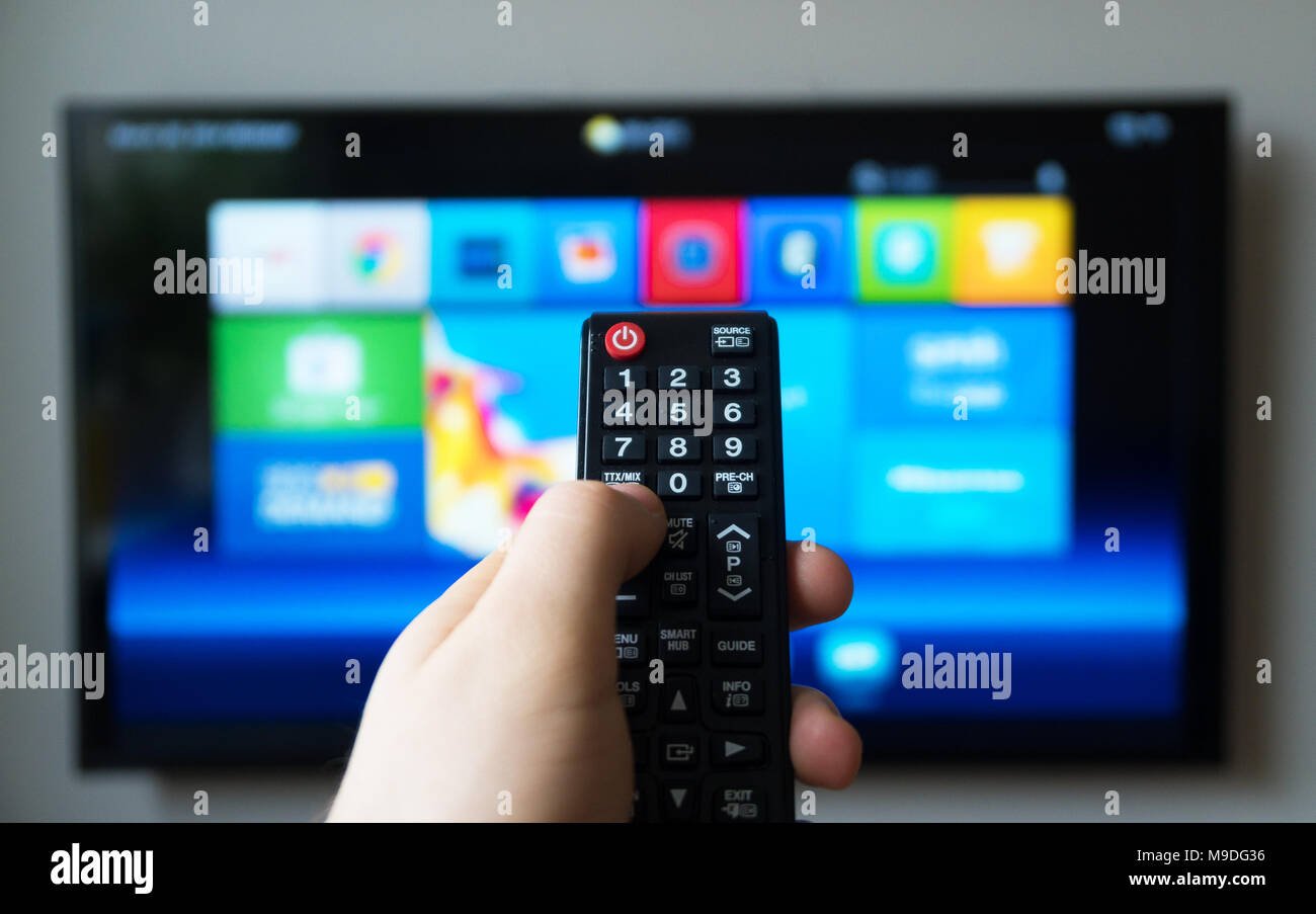 Hombre mano sujetando el mando a distancia de la televisión. TV inteligente. Foto de stock
