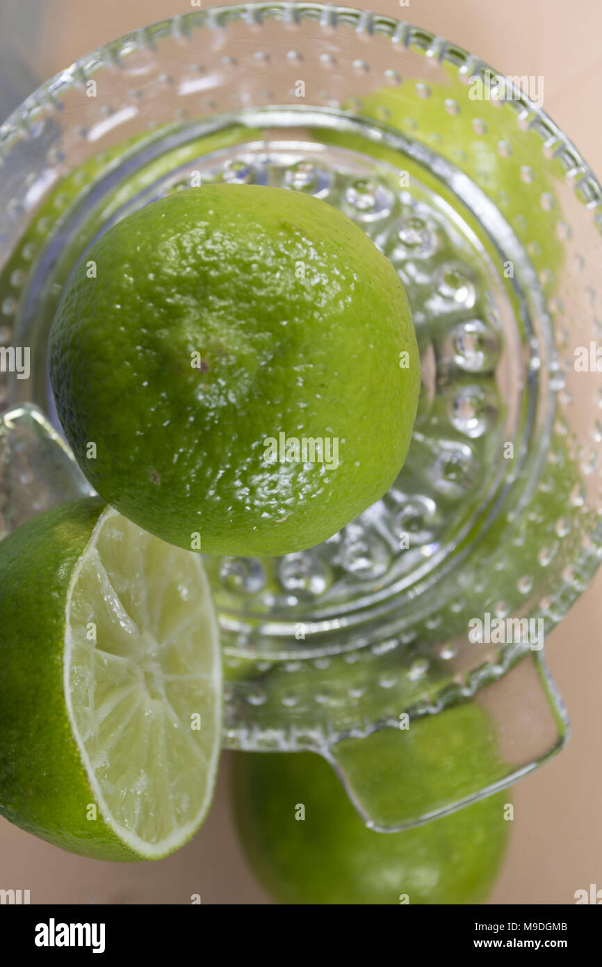 Limas verdes y vidrio de cal cerca alimentos exprimidora bodegón fotografía Foto de stock