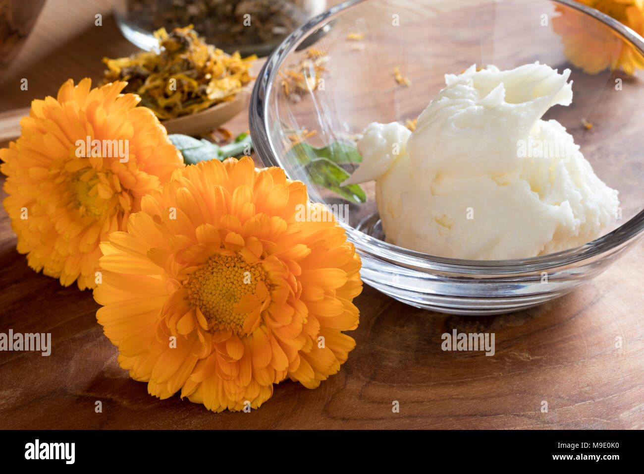 Naranja con flores de caléndula calendula crema en un tazón de vidrio sobre  una mesa de madera Fotografía de stock - Alamy