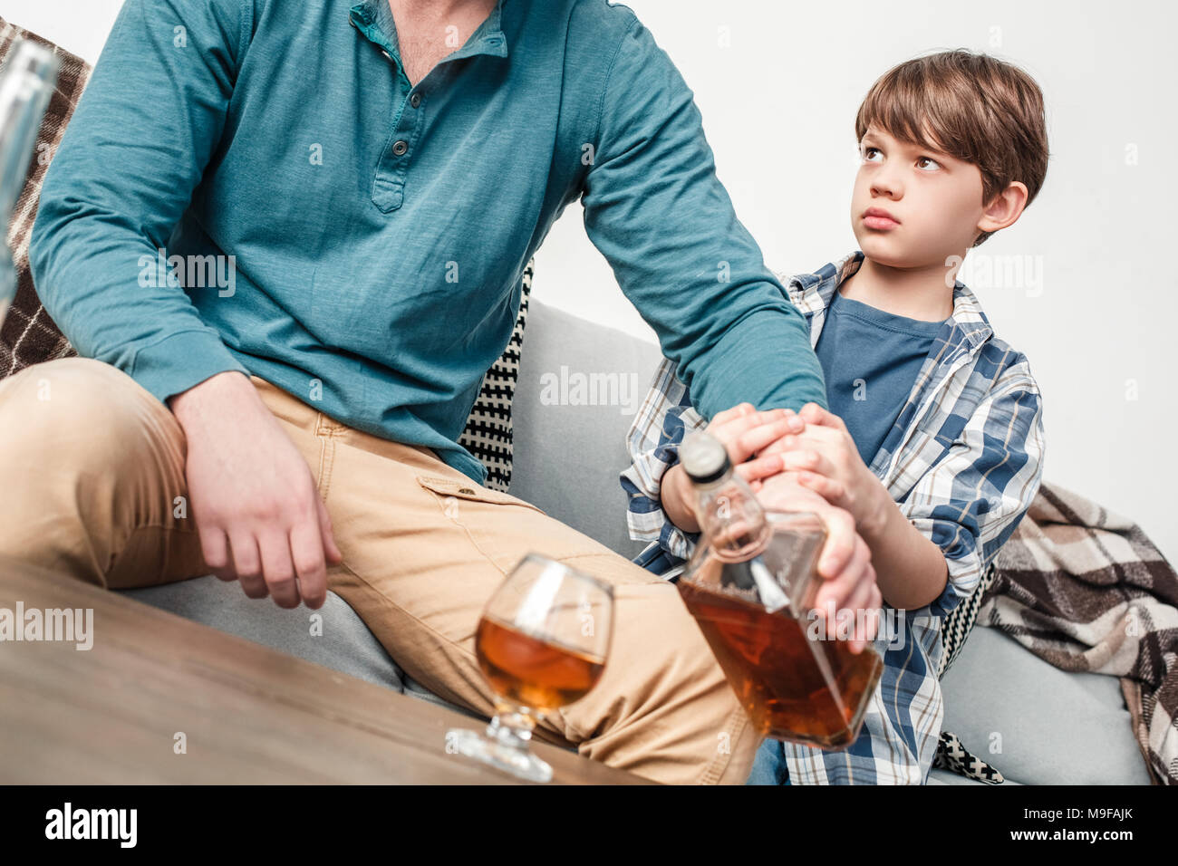 Chico y padre alcohólico en casa hijo sosteniendo la mano papá impedirle  frinking cerca de alcohol Fotografía de stock - Alamy