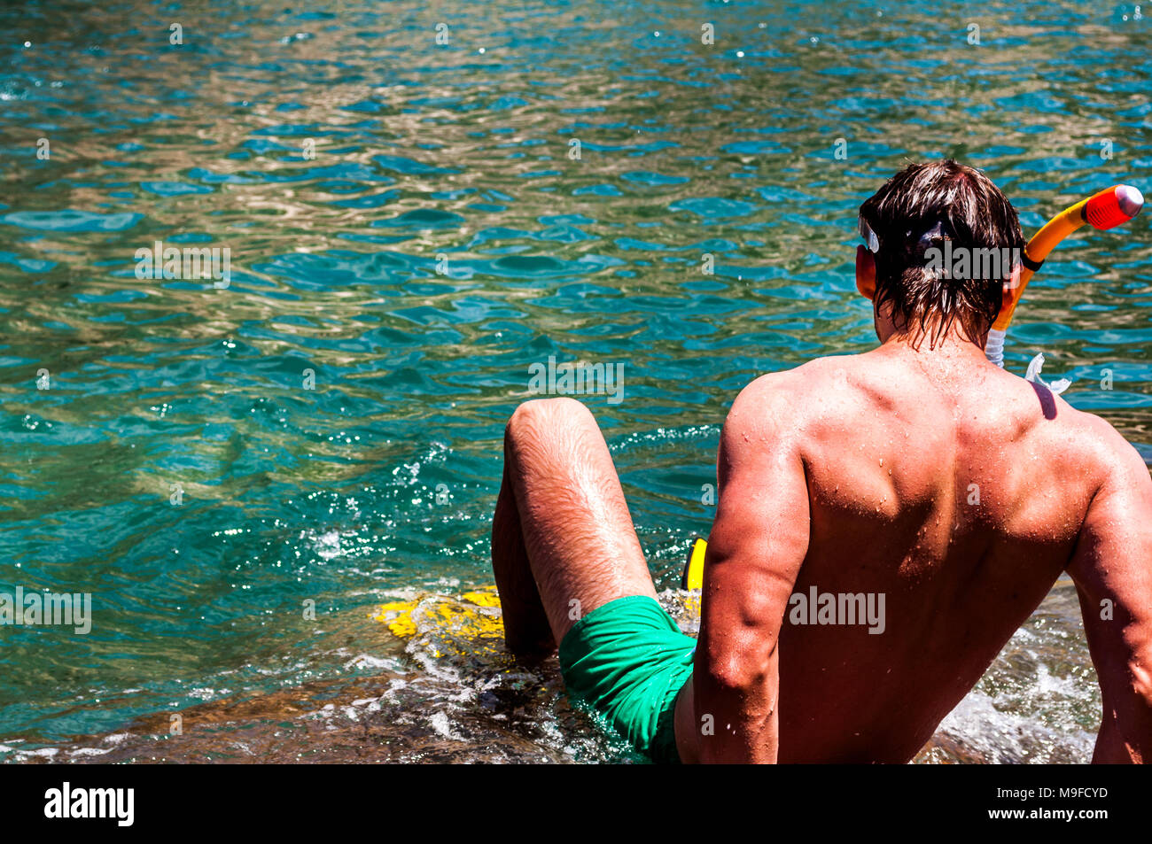 Hombre de buceo en aguas tropicales. El hombre prepara para bucear con su equipo de snorkeling Foto de stock