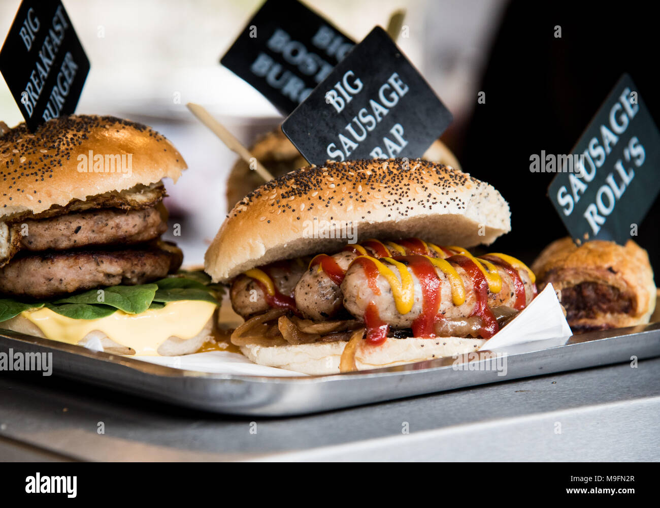 Deliciosos embutidos frescos servidos con verduras y cebolla roja en un bollo de pan fresco. Foto de stock
