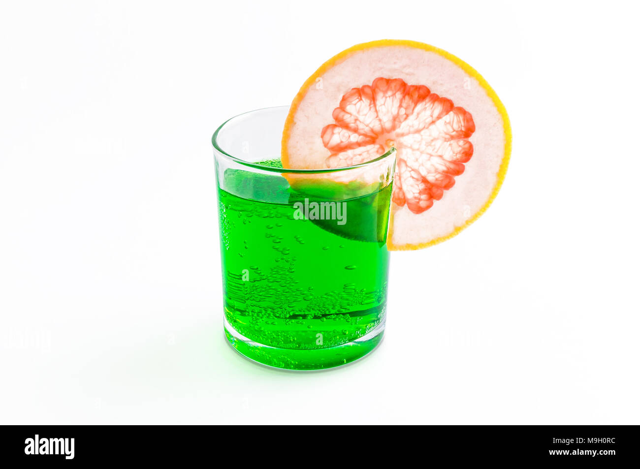 Cóctel de soda con pomelo verde en borde de un cristal transparente y aroma a menta de primavera y verano aislado sobre fondo blanco Fotografía de stock -