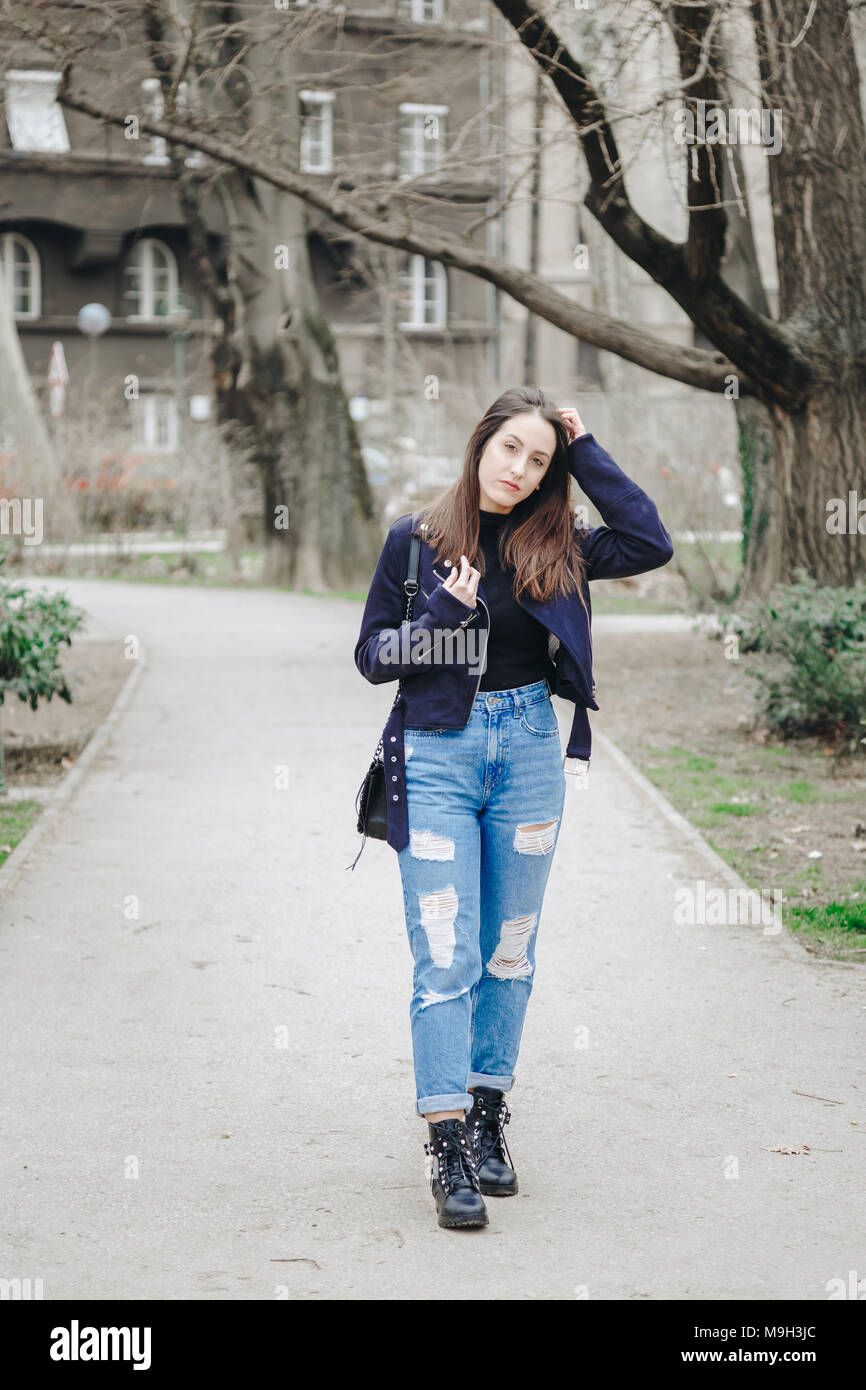 Ropa moda otoño detalles, joven elegante mujer vistiendo una chaqueta de  cuero de gamuza, ripped jeans y botines negro. moda sosteniendo un blogger  de moda Fotografía de stock - Alamy