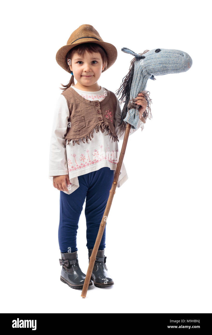 Linda niña vestida como un vaquero jugando con un caballo casero. Aislado  sobre un fondo blanco Fotografía de stock - Alamy