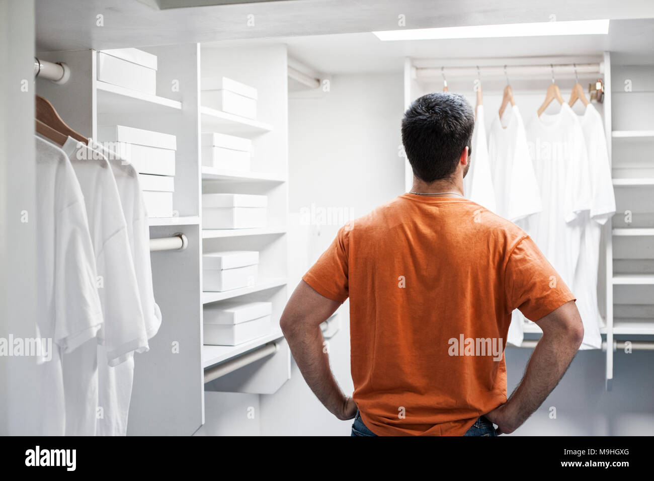 Hombre hispano en un armario lleno de ropa blanca Fotografía de stock -  Alamy