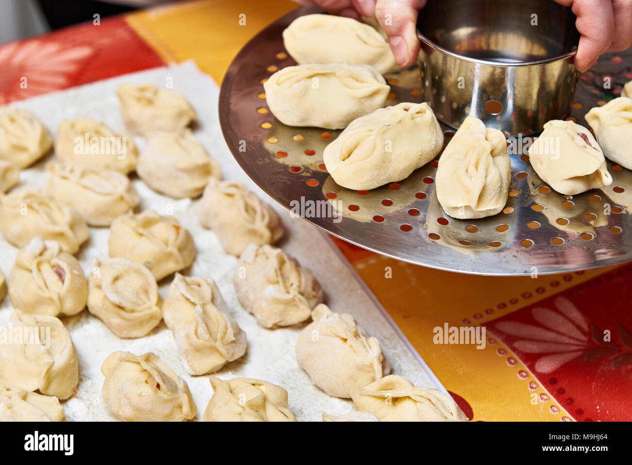 Womens manos con dumplings de manti y plataforma para cocer al vapor Foto de stock