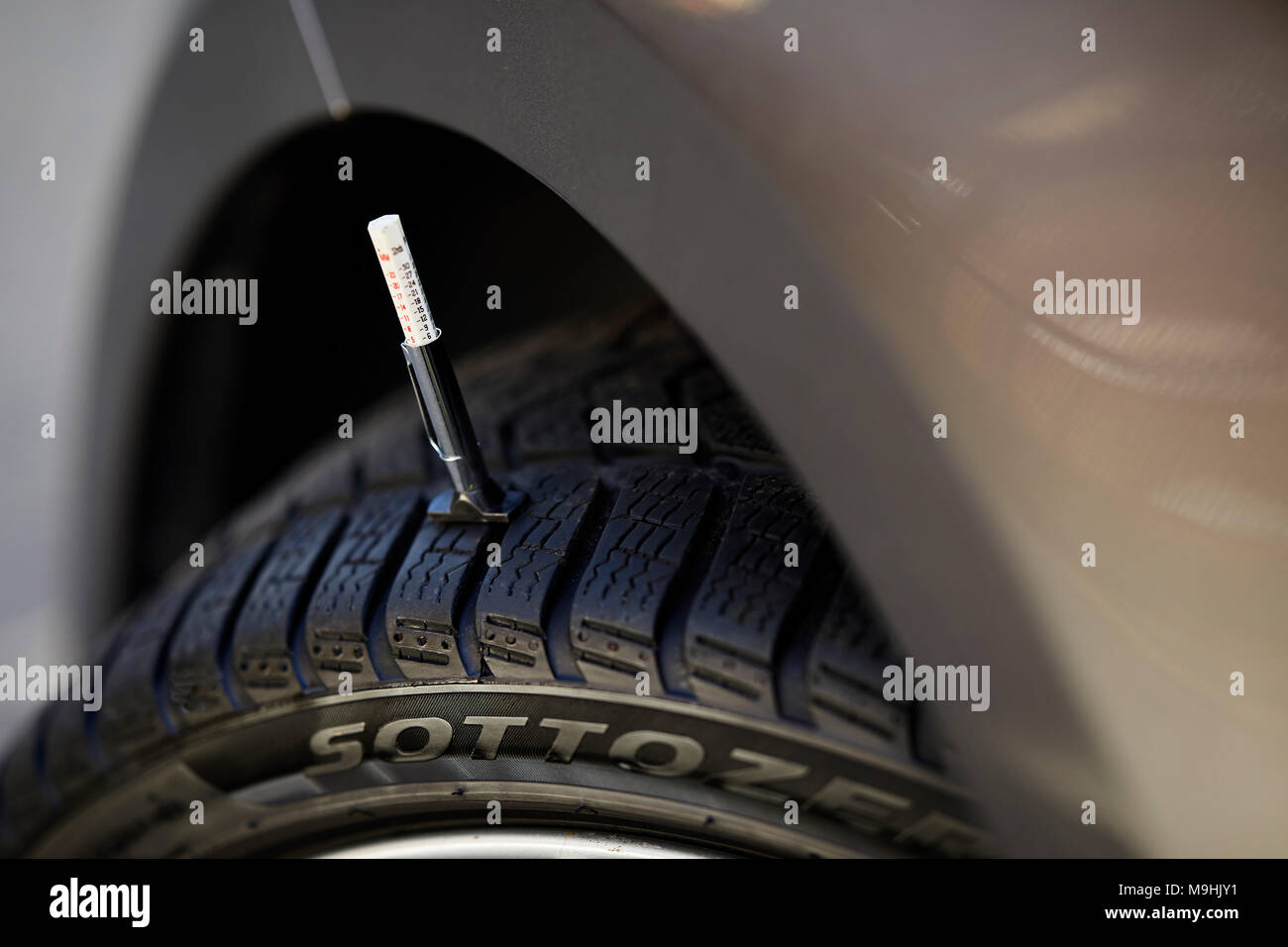 Tomar las lecturas del medidor de profundidad de la banda de rodadura del neumático Foto de stock