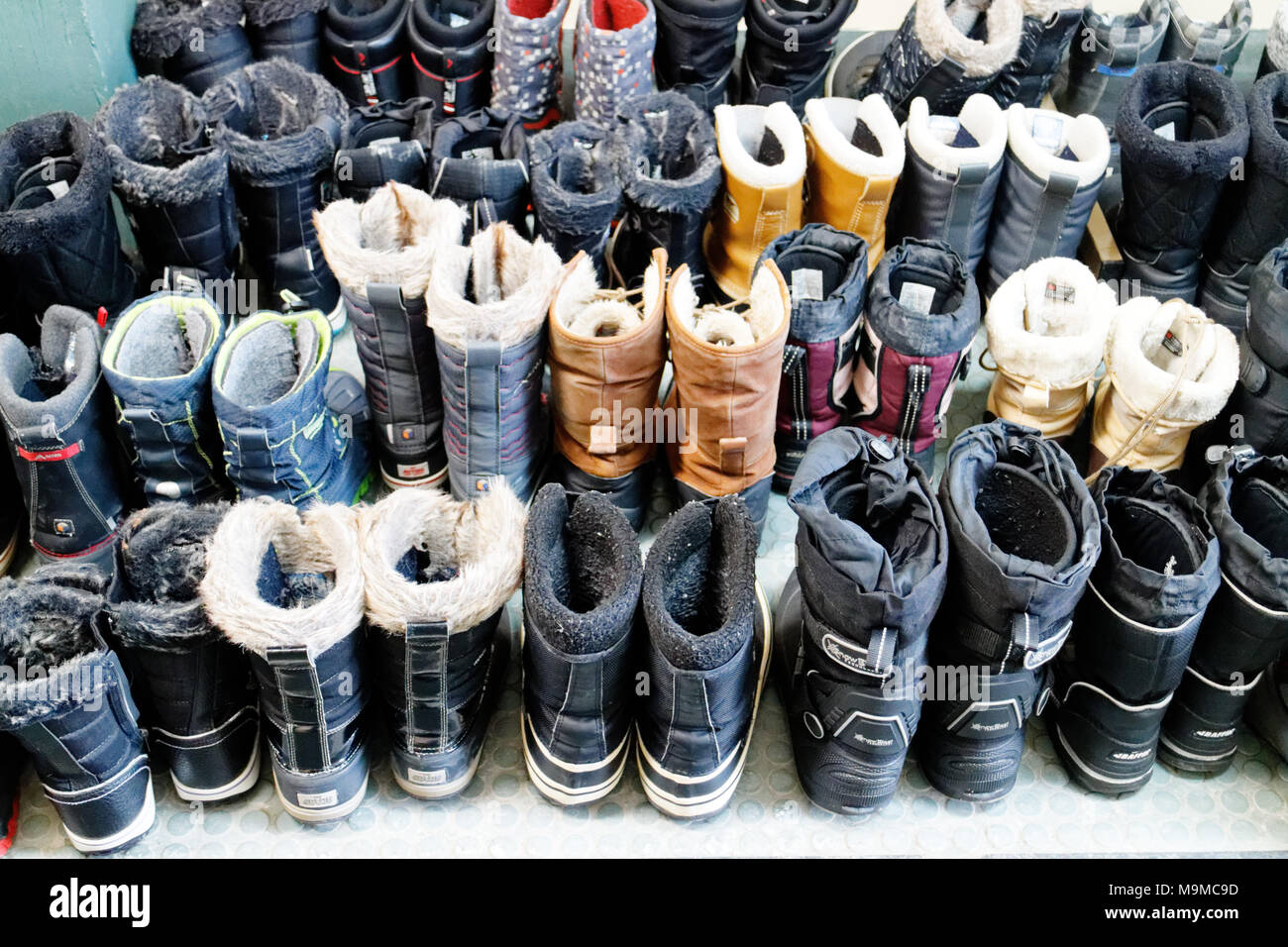 Sesenta y cinco pares de botas de invierno perfectamente alineadas en una estación de esquí de fondo de Quebec Foto de stock