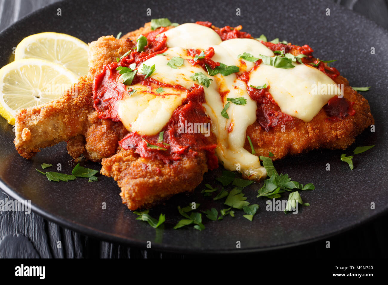 Milanesa a la napolitana chuleta de ternera empanada con queso mozzarella y salsa de tomate closeup horizontal en una placa. Foto de stock