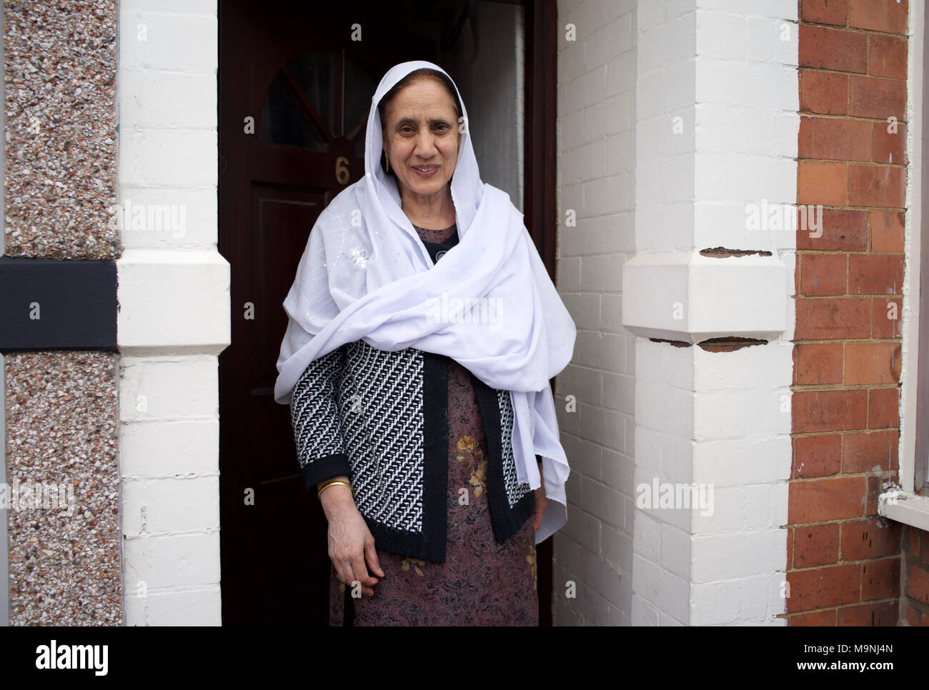 Mujer pakistaní, llevar velo, de pie en la puerta de casa - Rugby, Inglaterra Foto de stock