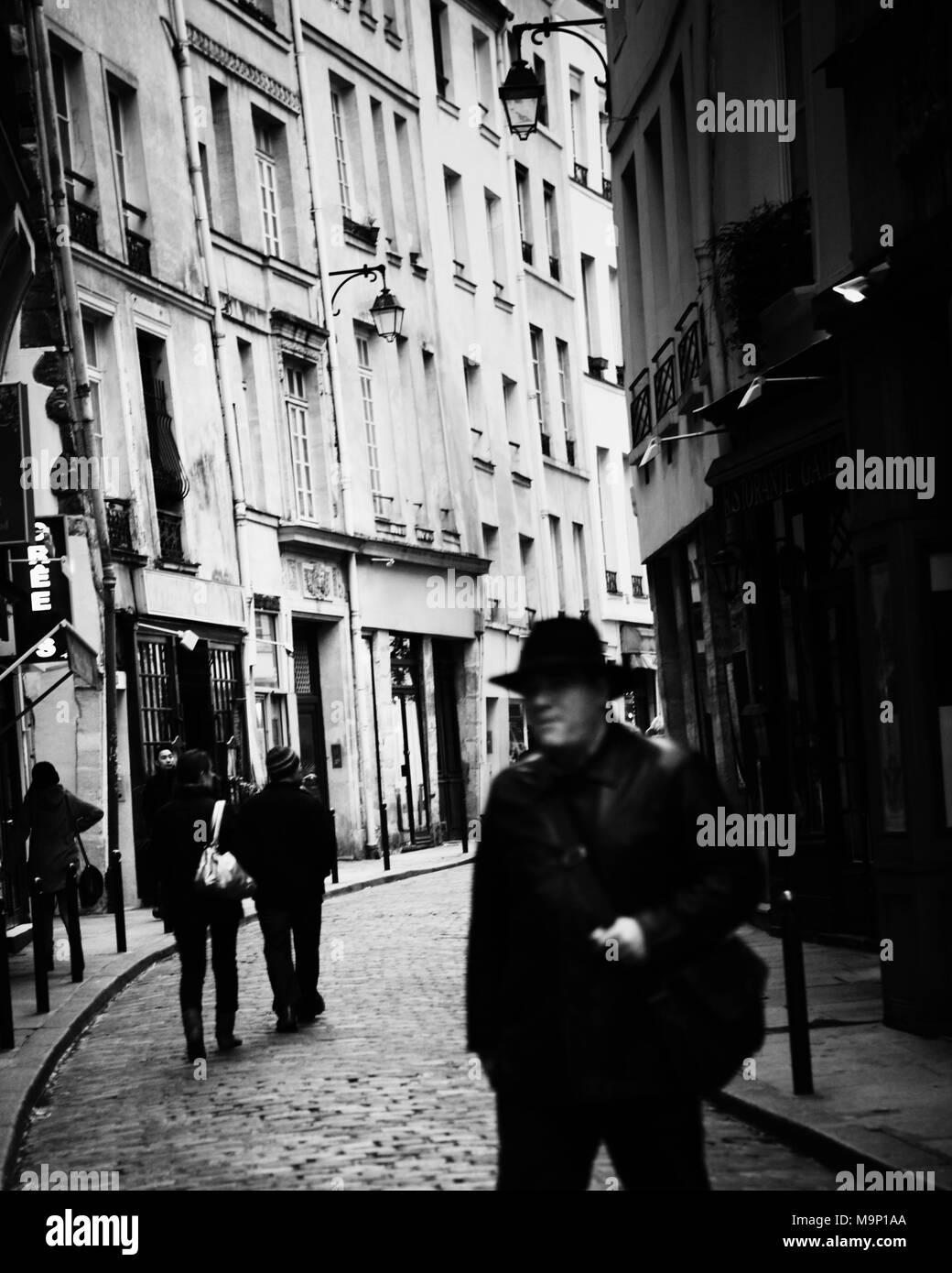 Típica estrecha calle de adoquines en París con un hombre en primer plano. Foto de stock
