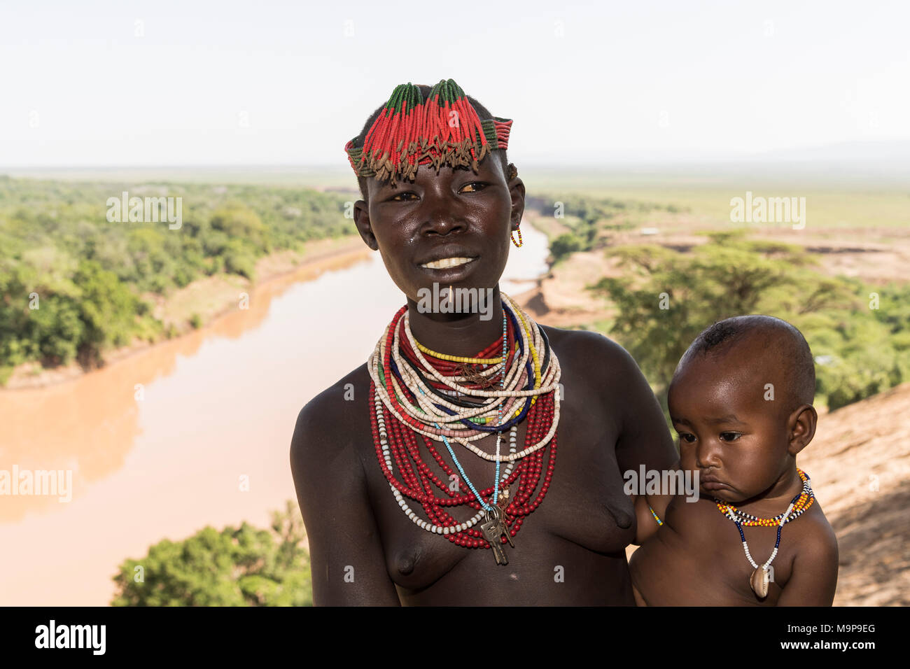 Mujer joven con un bebé, con la cabeza y collar, verificar la tribu, omo River, las naciones del Sur las Nacionalidades y los pueblos de la región Foto de stock