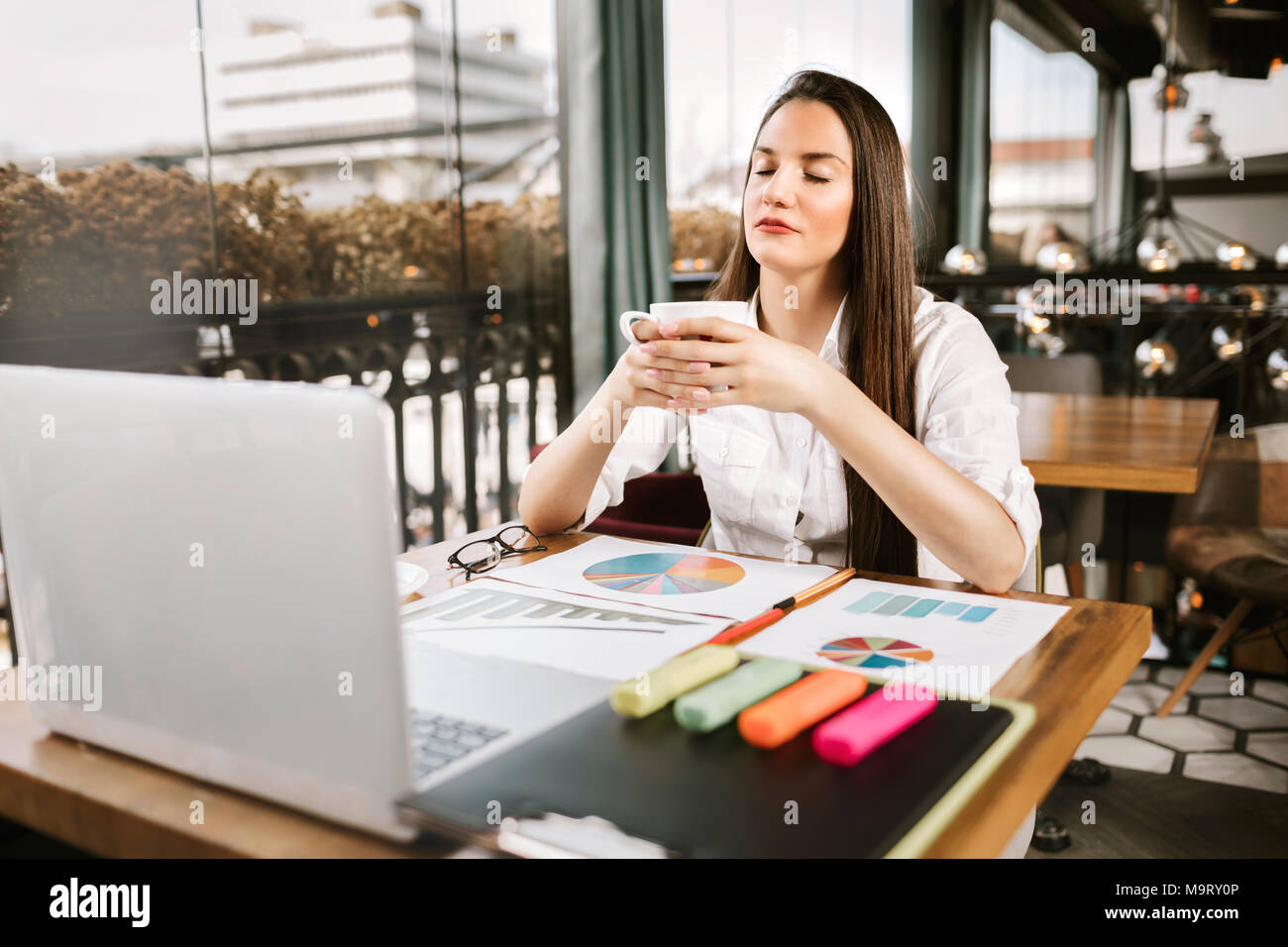 La empresaria o mujer joven con gafas haciendo pausa café en el trabajo. Café Concepto de relajación. Foto de stock