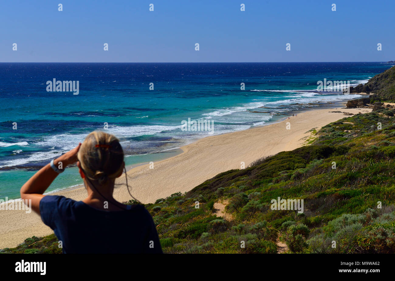 Mujer mirando al norte a lo largo de Yallingup playa hacia Cape Naturaliste Faro ,Yallingup, Australia Occidental Foto de stock
