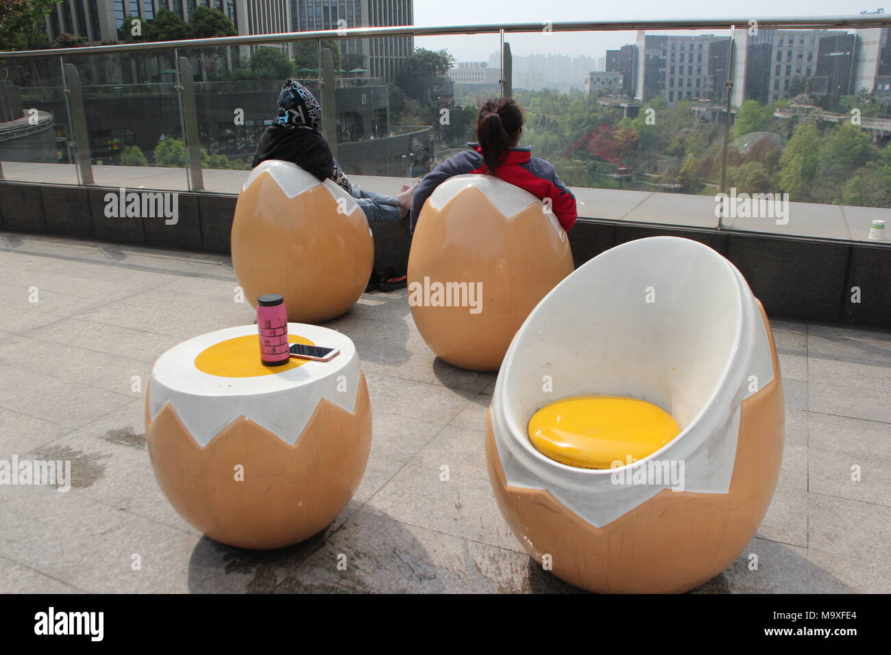 Chongqin, China. 29 Mar, 2018. A los turistas disfrutar de la vista  mientras están sentados en sillas en forma de huevo en una plaza en el  sudoeste de China de Chongqing. Crédito: