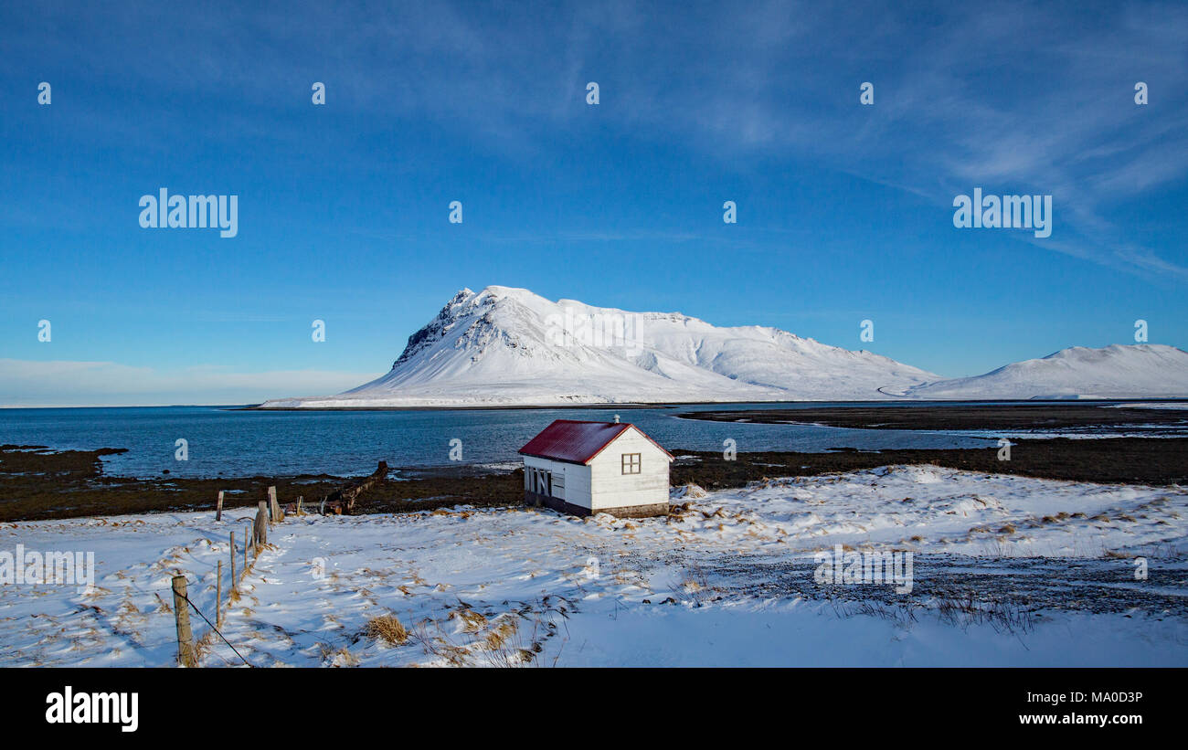 Un cobertizo con techo rojo al borde del mar en medio de un duro invierno en Islandia. 2015 fue un invierno particularmente duras en Islandia. Foto de stock
