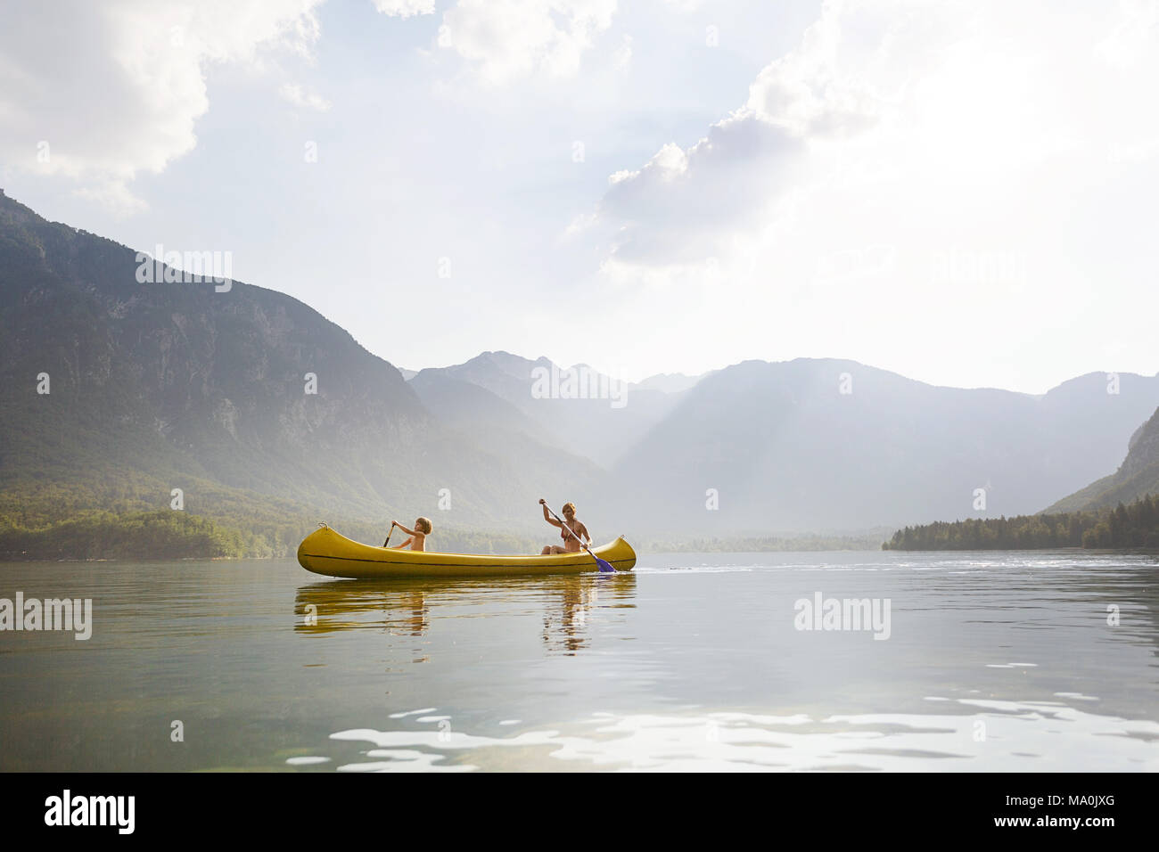 Una madre y su hijo de cinco años canoa en un lago alpino en los Alpes Julianos Foto de stock