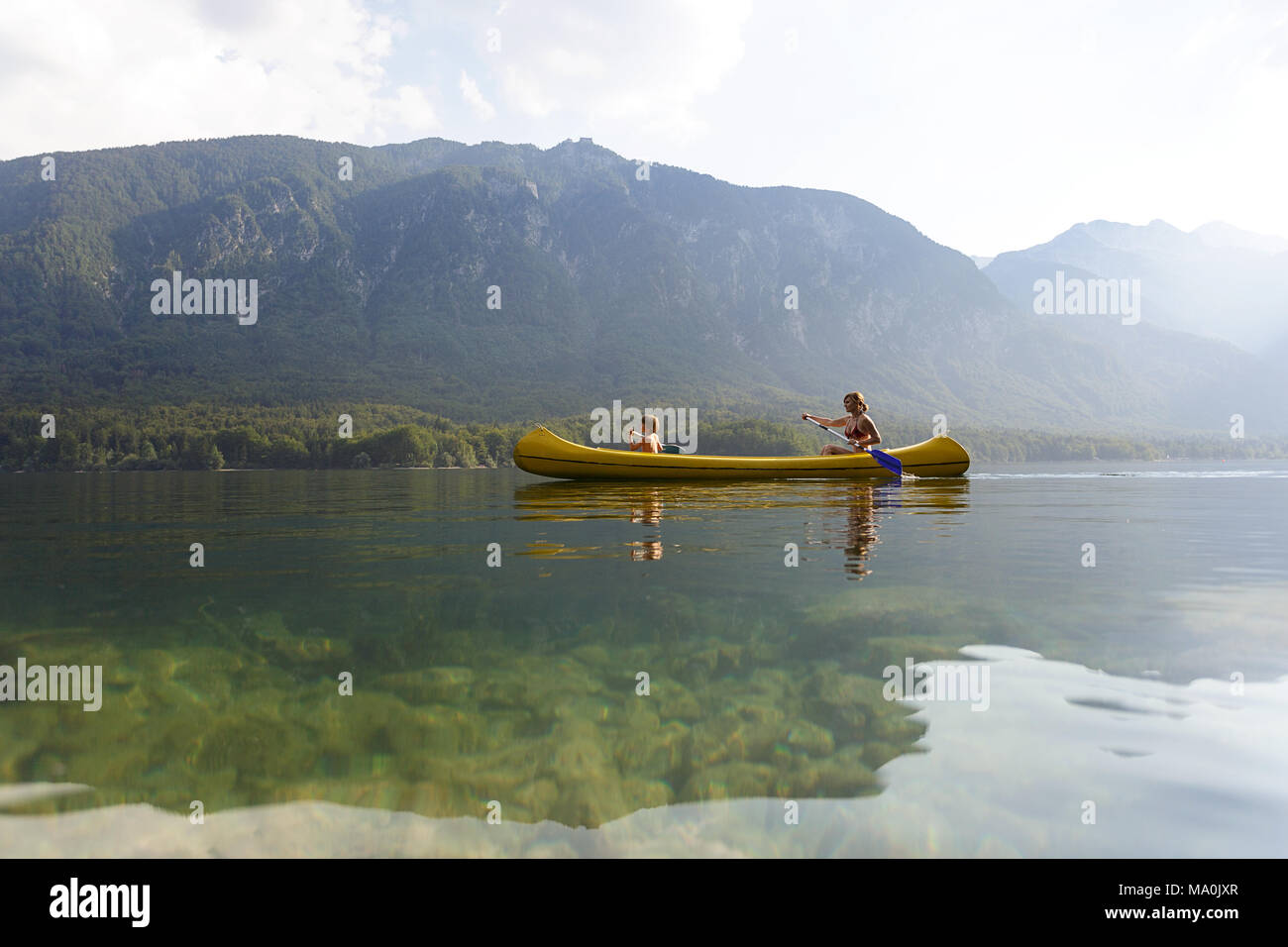 Una madre y su hijo de cinco años canoa en un lago alpino en los Alpes Julianos Foto de stock