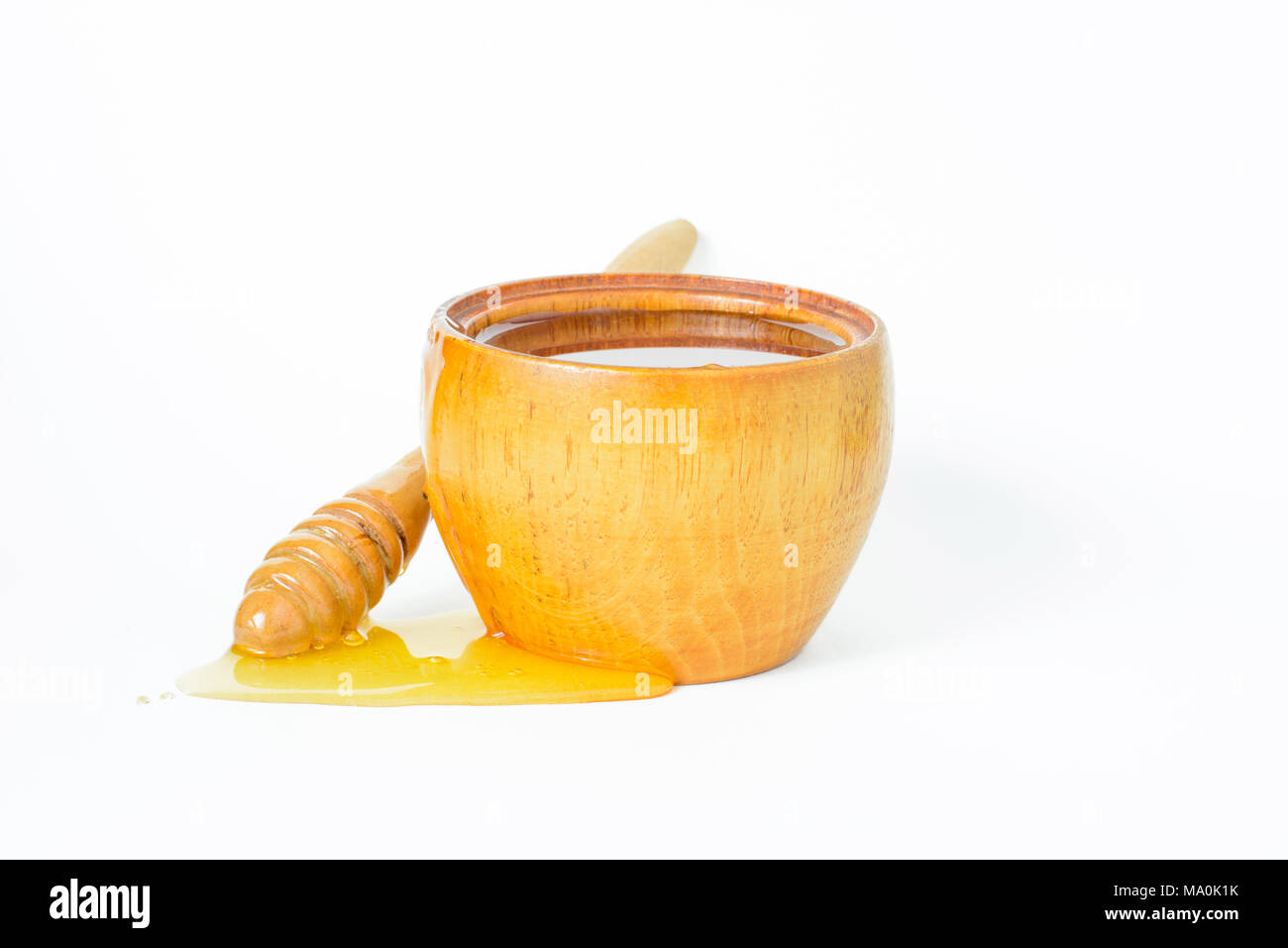 La miel en un recipiente de madera y un penetrador de miel. Foto de stock