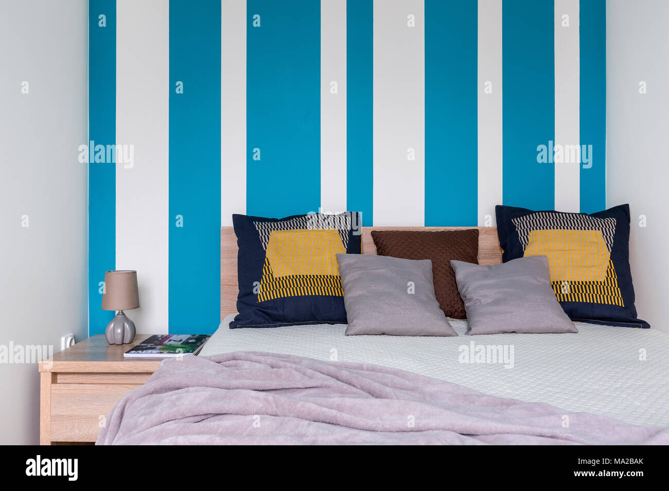 https://c8.alamy.com/compes/ma2bak/acogedor-dormitorio-con-cama-grande-cojines-decorativos-y-paredes-a-rayas-en-blanco-y-azul-ma2bak.jpg