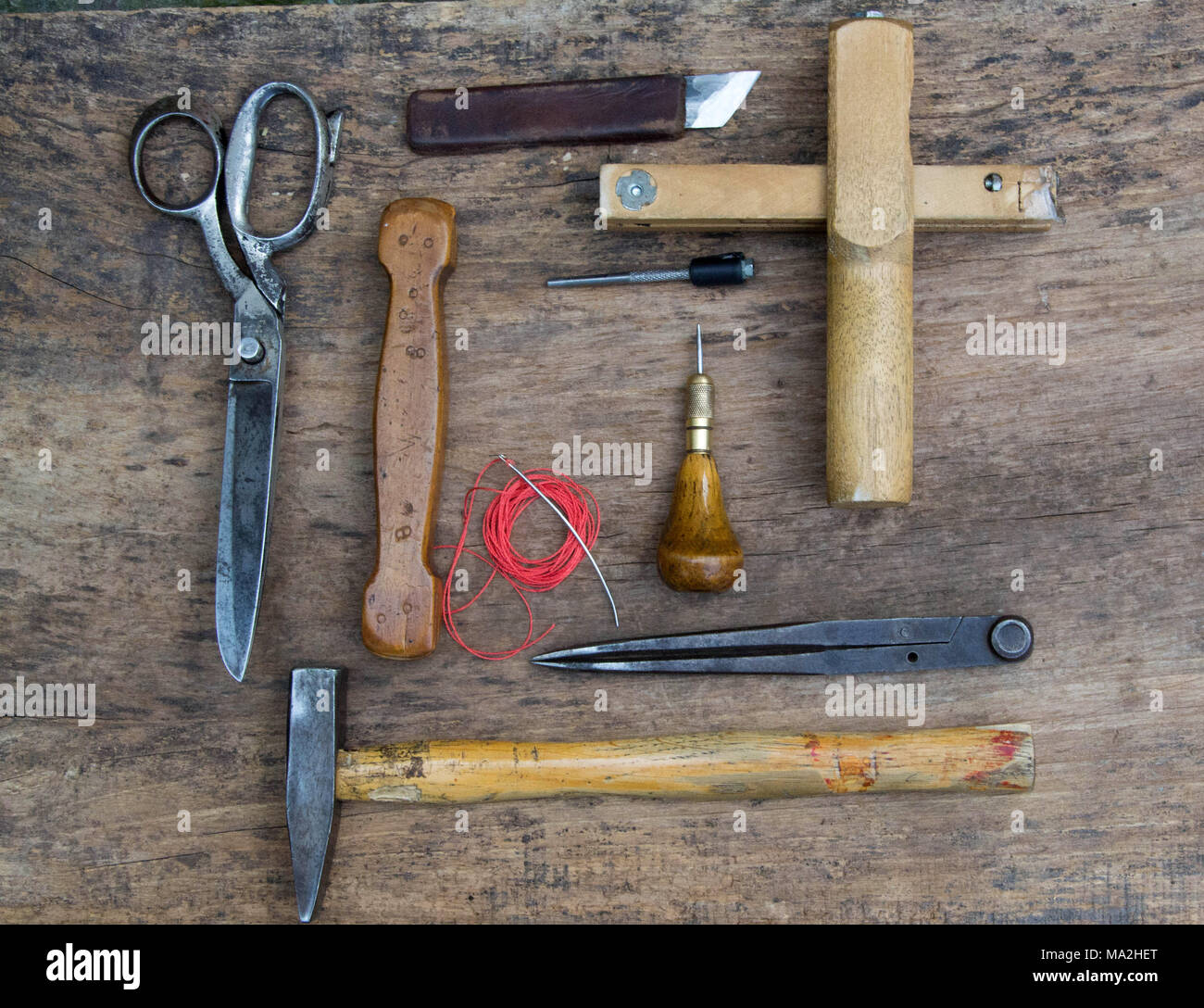 Herramientas de artesanía de cuero en una madera vieja backgrounde.  Escritorio de trabajo artesano . Pieza de trabajo y ocultar herramientas  hechas a mano sobre una mesa de trabajo Fotografía de stock -