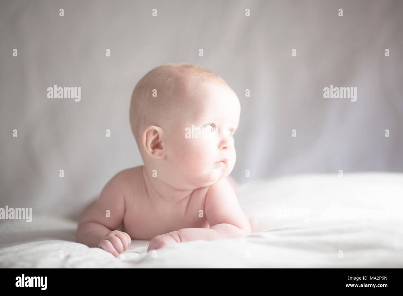 Muy lindo bebé niño mirando hacia la luz con expresión contemplativa Foto de stock