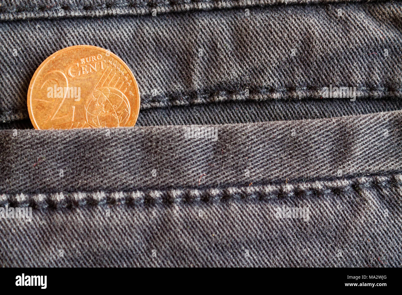 Euro con una denominación de la moneda de 2 céntimo de euro en el bolsillo de los pantalones vaqueros azules desgastados Foto de stock